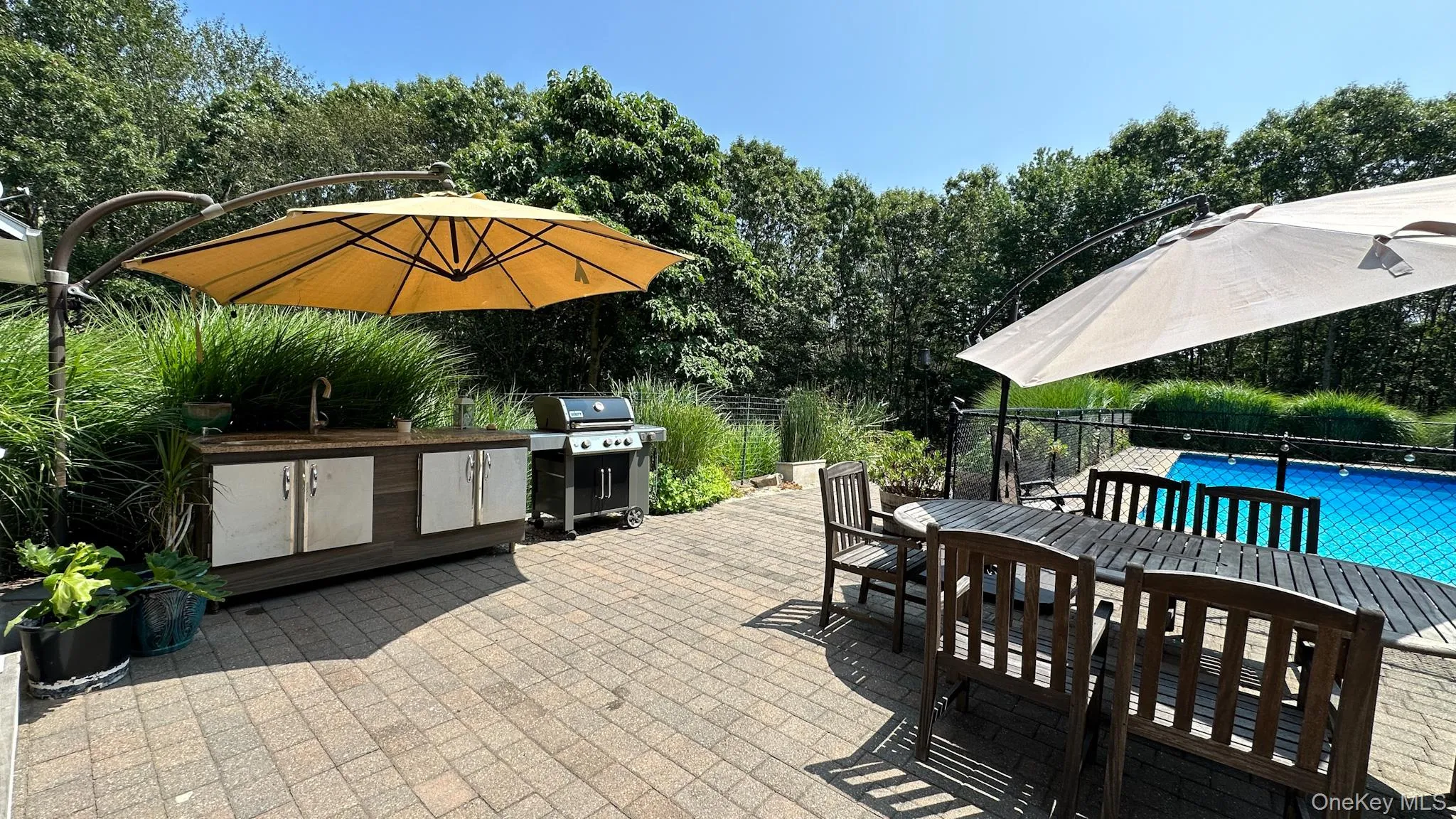 View of patio / terrace featuring a fenced in pool, an outdoor kitchen, outdoor dining space, a sink, and a grill View of patio / terrace featuring a fenced in pool, an outdoor kitchen, outdoor dining space, a sink, and a grill