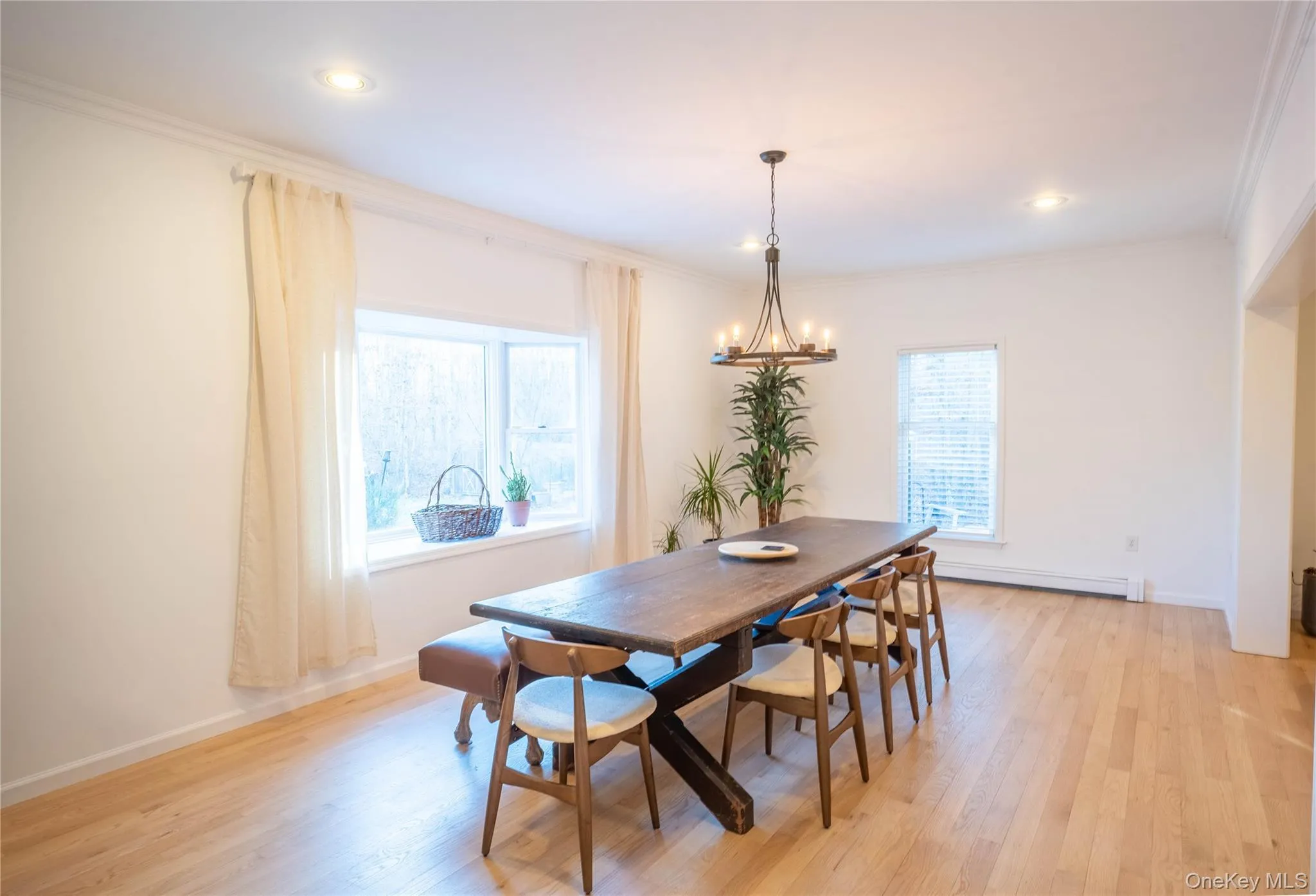 Dining space with ornamental molding, a chandelier, and light wood-style floors Dining space with ornamental molding, a chandelier, and light wood-style floors