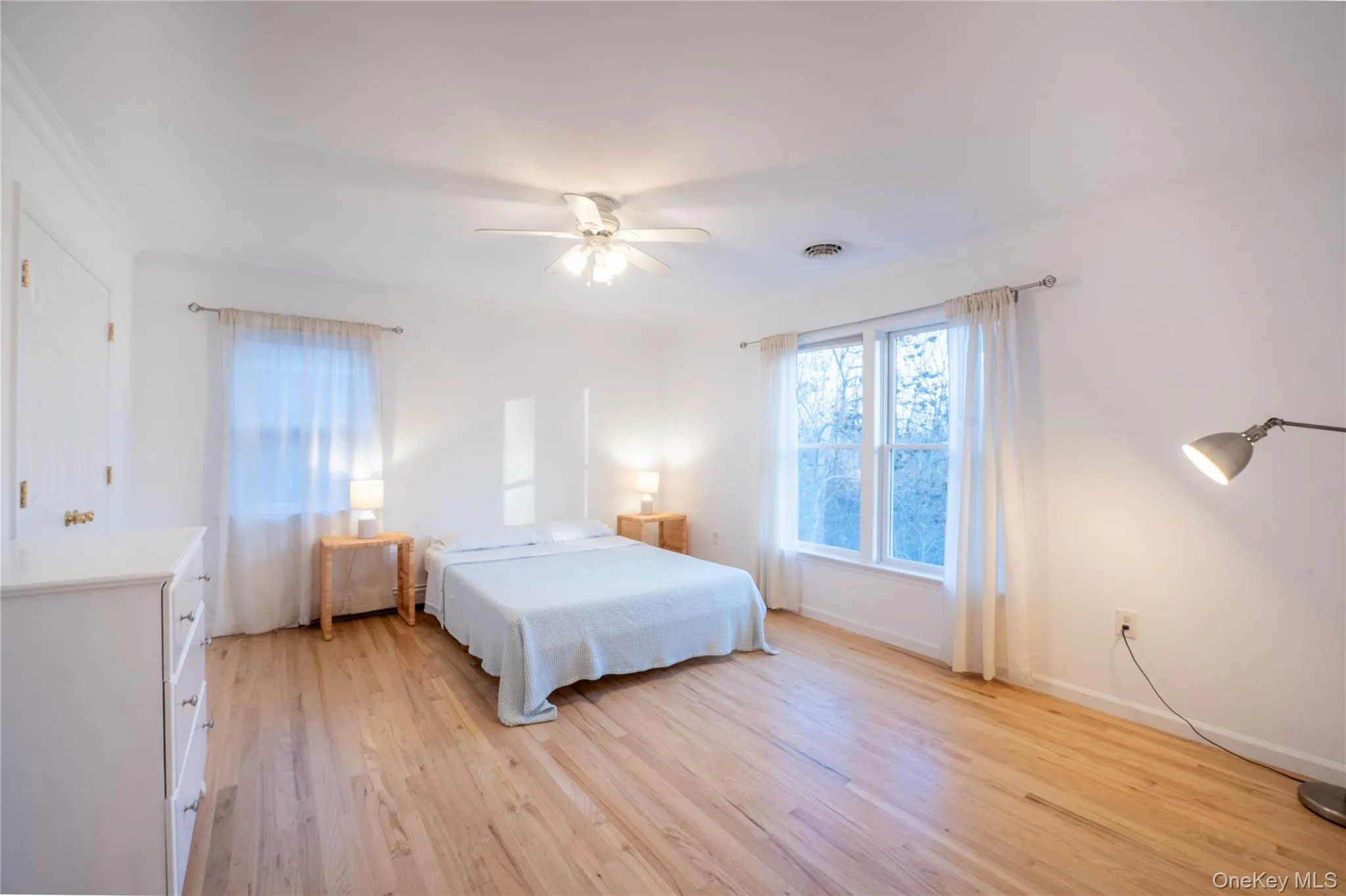Bedroom featuring baseboards, light wood-style flooring, visible vents, and crown molding Bedroom featuring baseboards, light wood-style flooring, visible vents, and crown molding