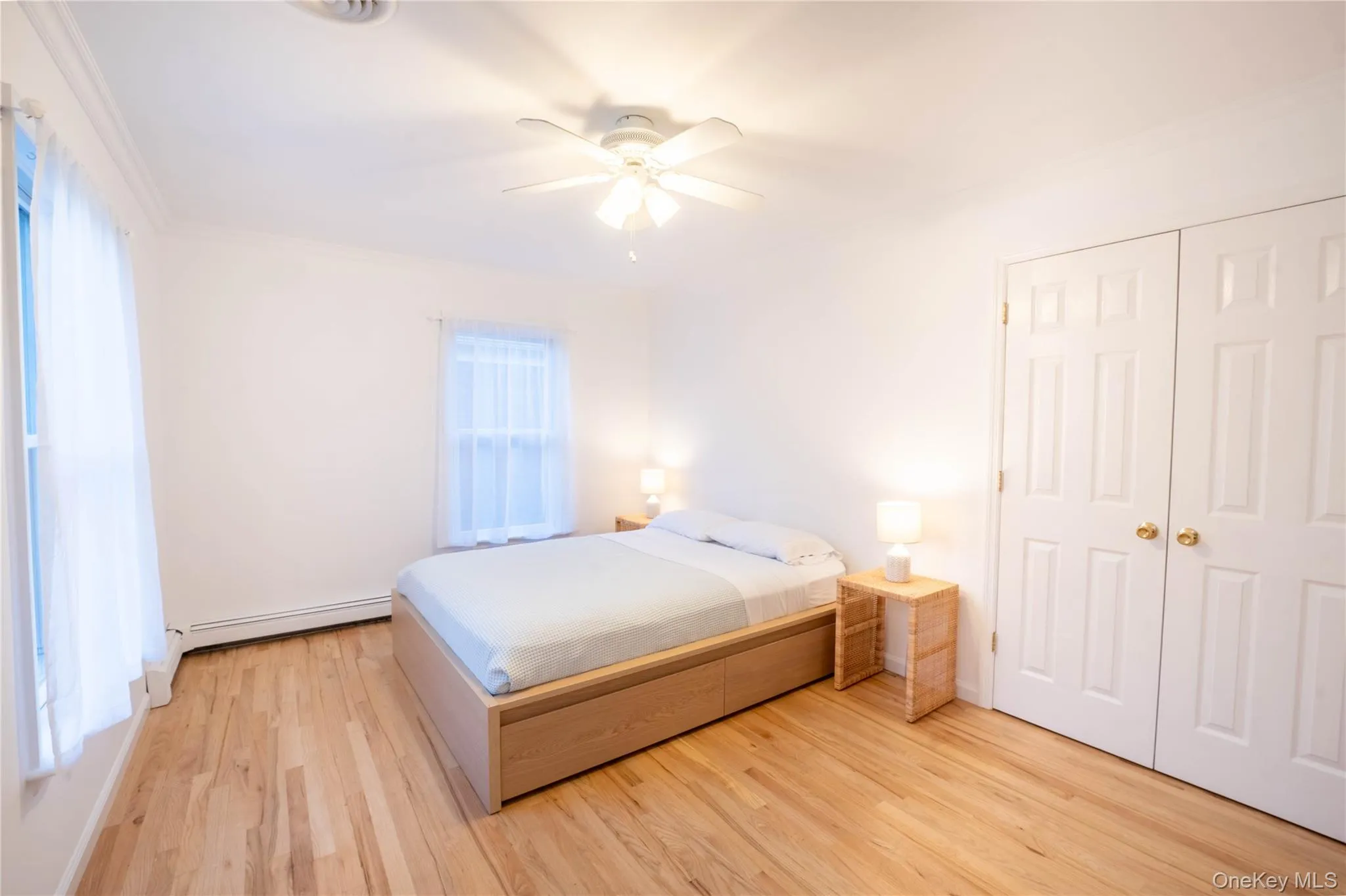 Unfurnished bedroom with a closet, light wood-style flooring, baseboard heating, ornamental molding, and ceiling fan Unfurnished bedroom with a closet, light wood-style flooring, baseboard heating, ornamental molding, and ceiling fan