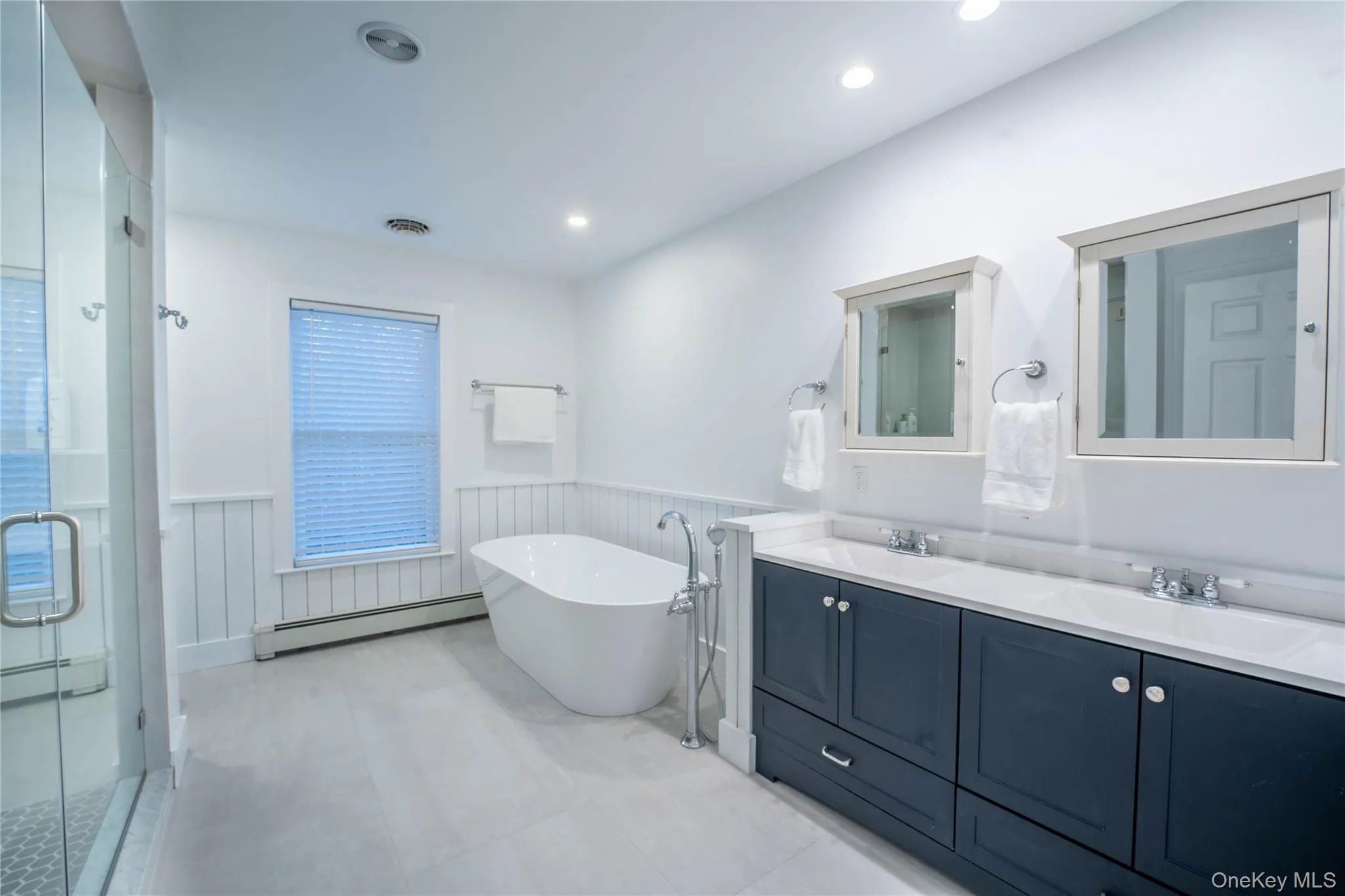 Bathroom featuring a baseboard heating unit, wainscoting, a sink, and visible vents Bathroom featuring a baseboard heating unit, wainscoting, a sink, and visible vents