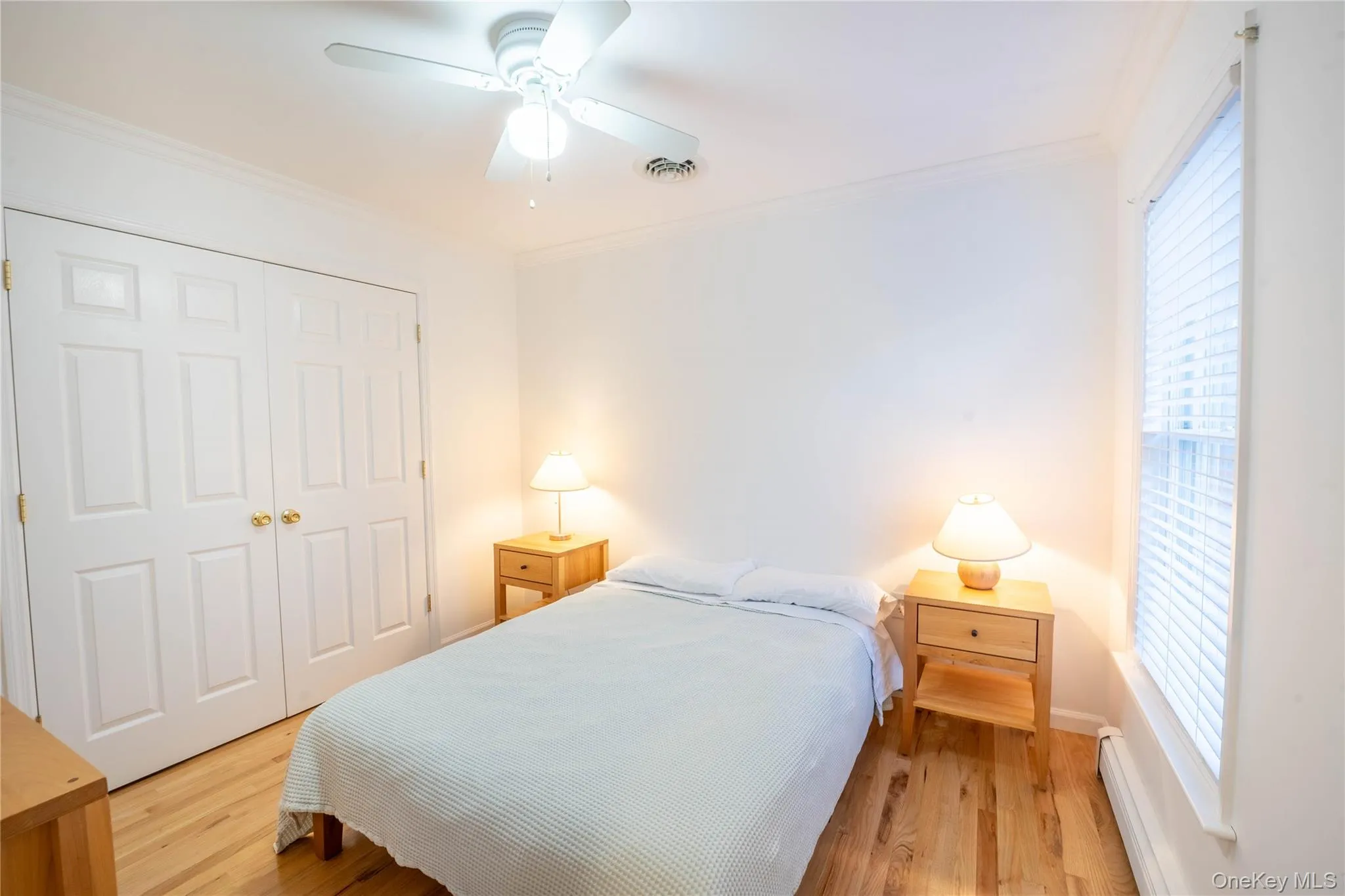 Bedroom with multiple windows, a closet, wood finished floors, and crown molding Bedroom with multiple windows, a closet, wood finished floors, and crown molding