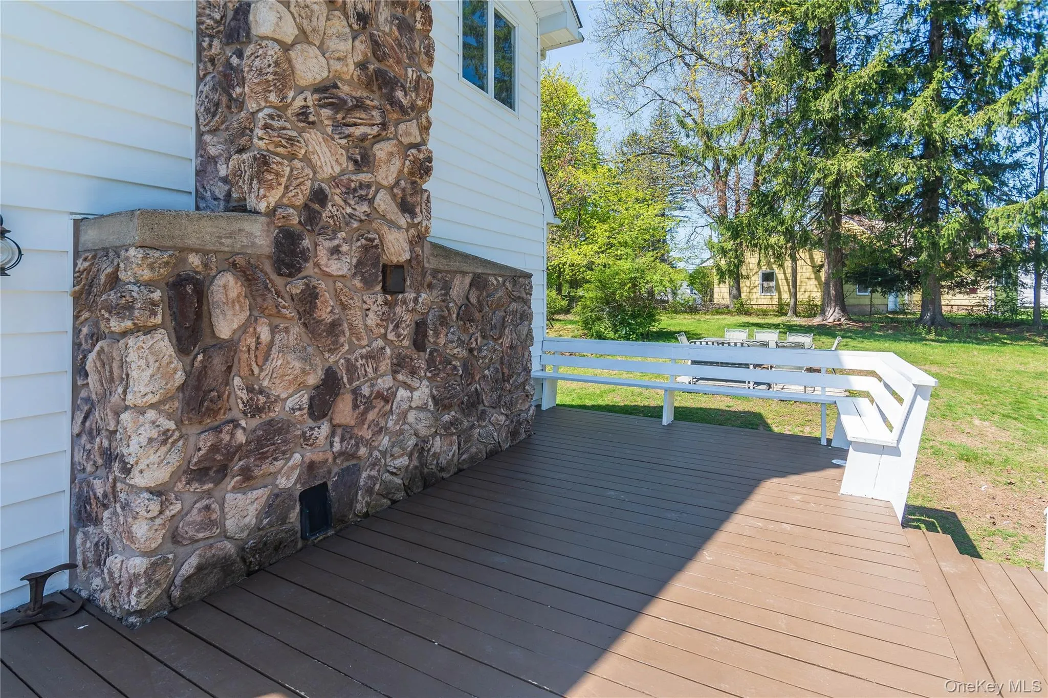 Closer view of deck with stone fireplace in well maintained condition Closer view of deck with stone fireplace in well maintained condition