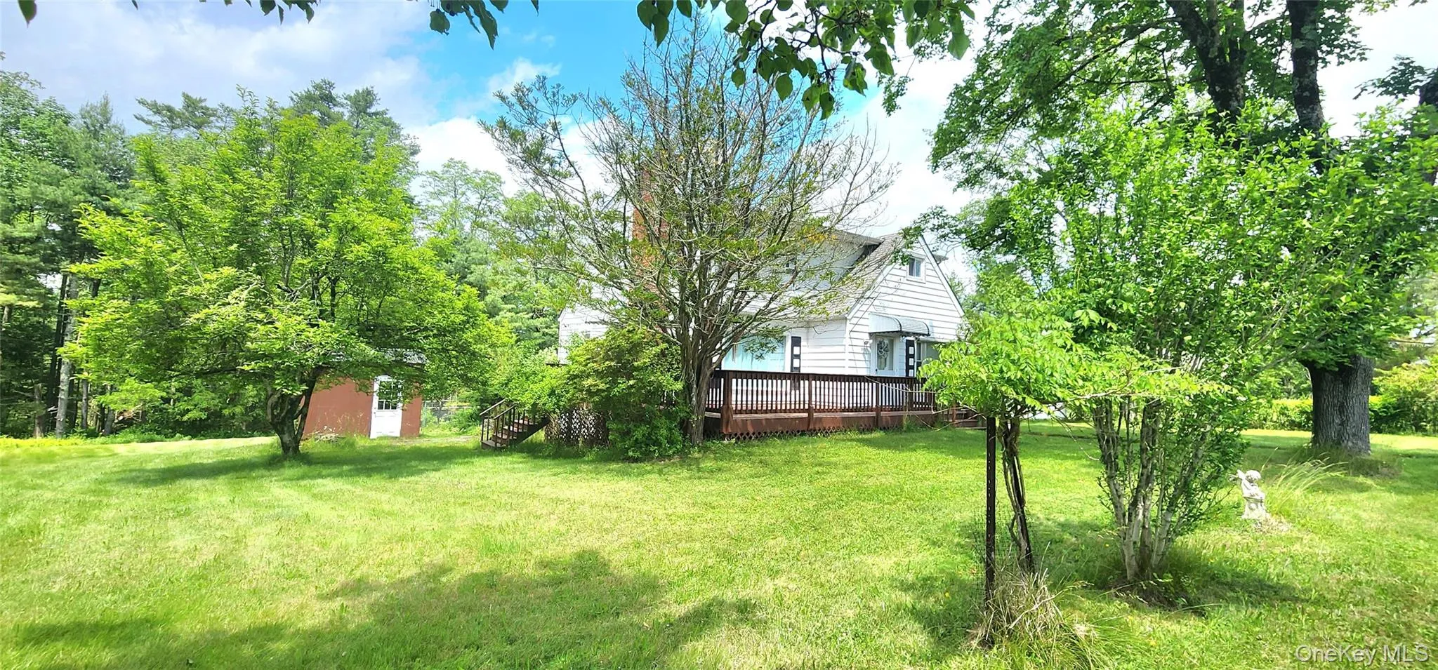 View of green lawn featuring a deck View of green lawn featuring a deck