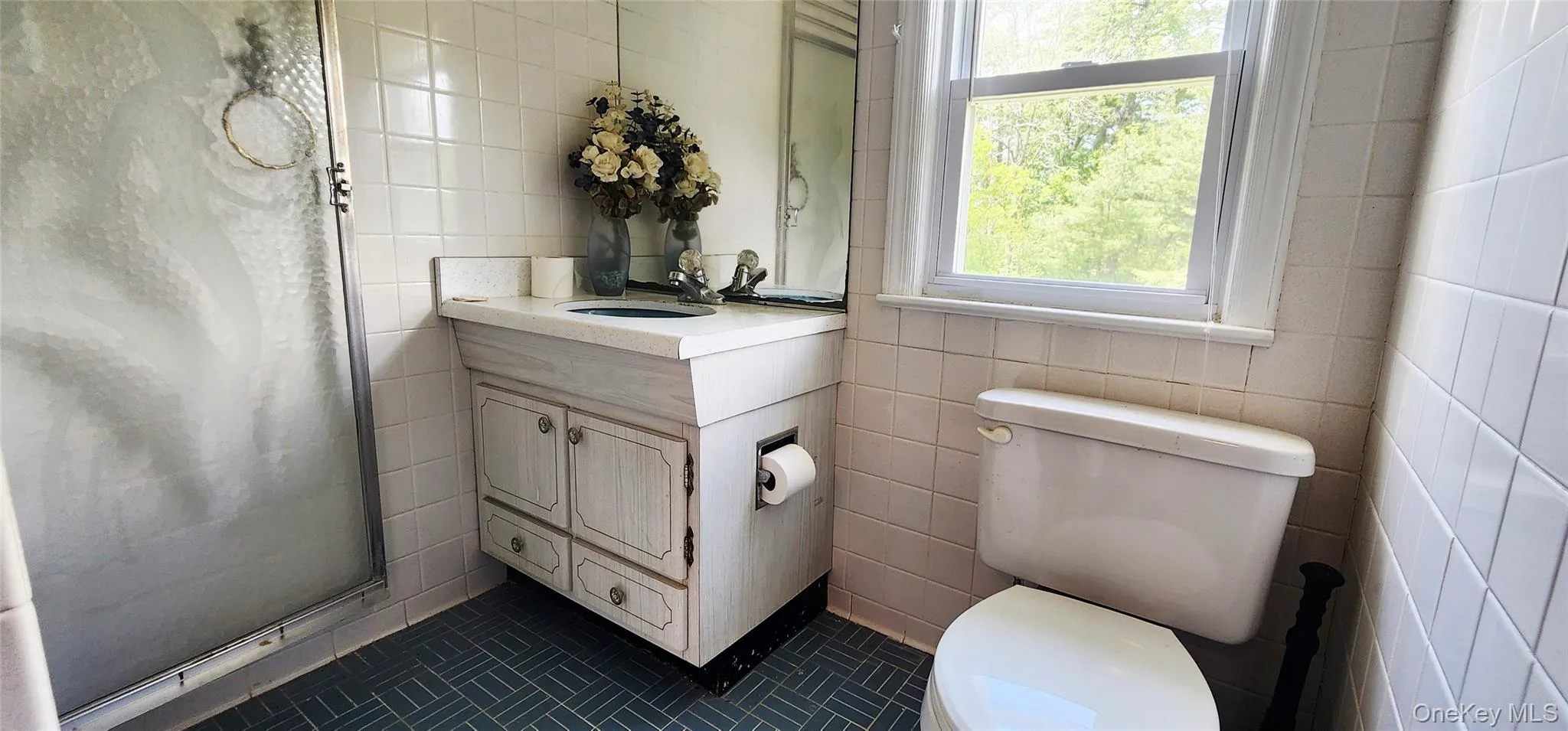 Full bathroom featuring tile walls, vanity, tile patterned flooring, and a stall shower Full bathroom featuring tile walls, vanity, tile patterned flooring, and a stall shower