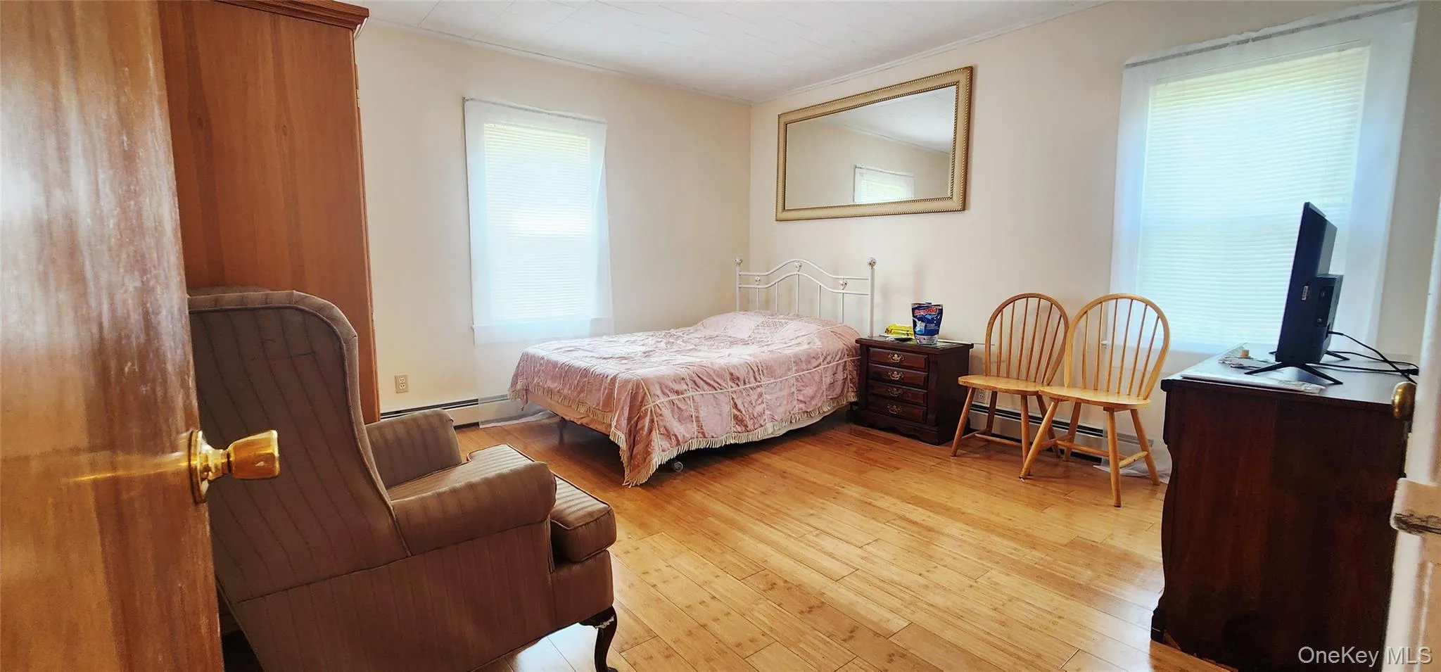 Bedroom with wood finished floors and a baseboard heating unit Bedroom with wood finished floors and a baseboard heating unit