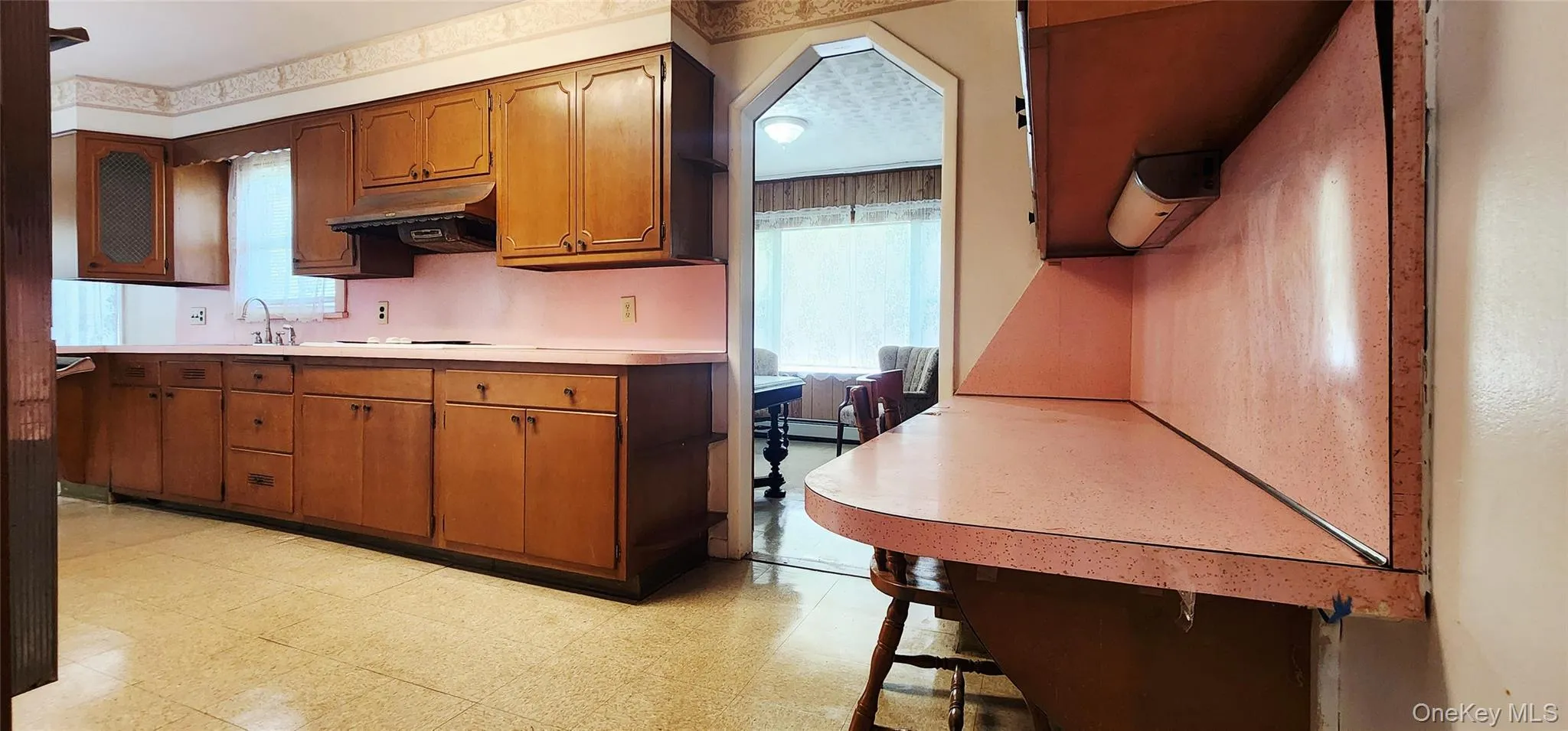 Kitchen featuring light countertops, under cabinet range hood, light flooring, and brown cabinets Kitchen featuring light countertops, under cabinet range hood, light flooring, and brown cabinets