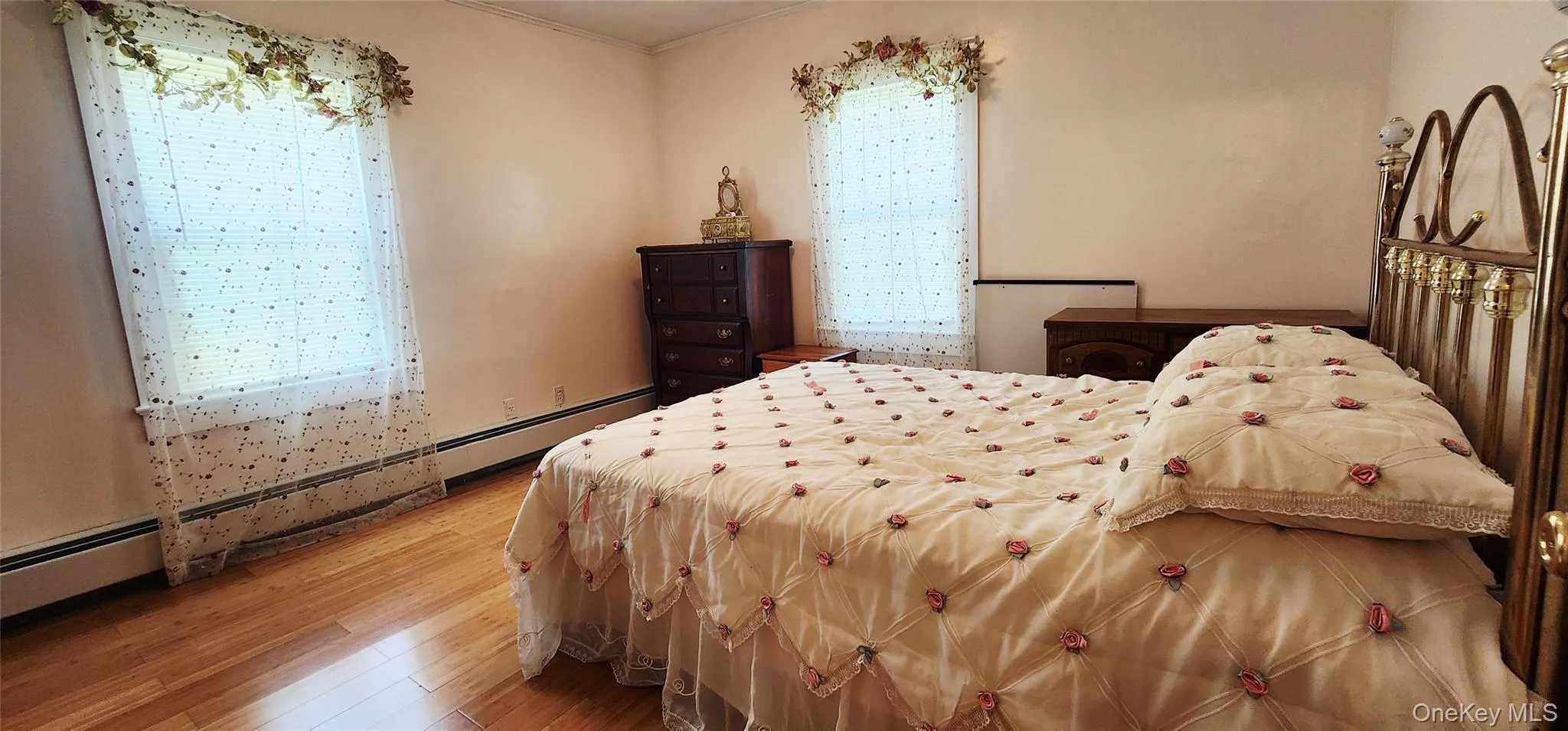 Bedroom with light wood-style flooring, multiple windows, baseboard heating, and ornamental molding Bedroom with light wood-style flooring, multiple windows, baseboard heating, and ornamental molding
