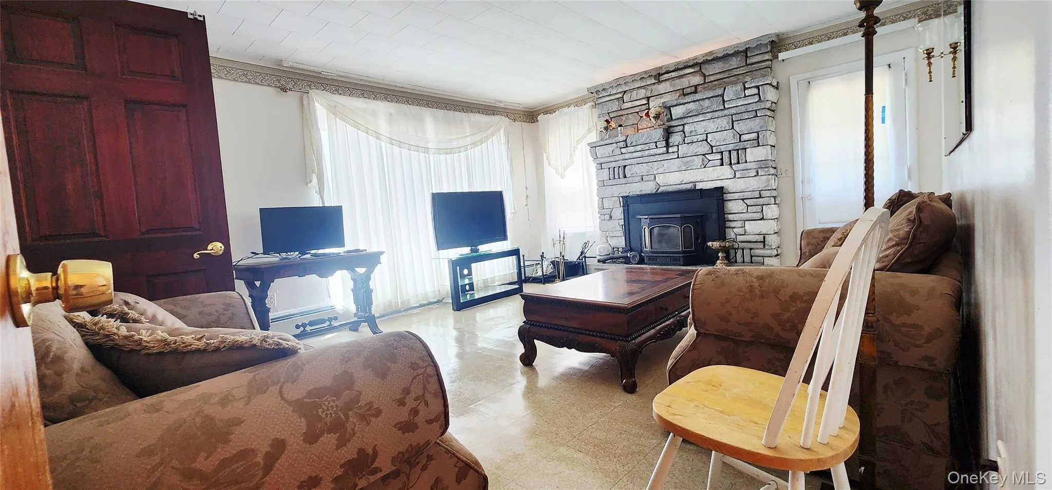 Living area featuring a wood stove and light floors Living area featuring a wood stove and light floors