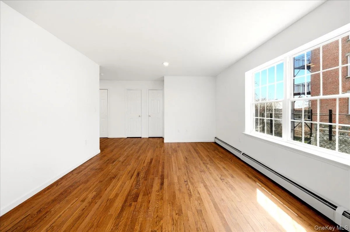 Empty room featuring baseboard heating and wood finished floors Empty room featuring baseboard heating and wood finished floors