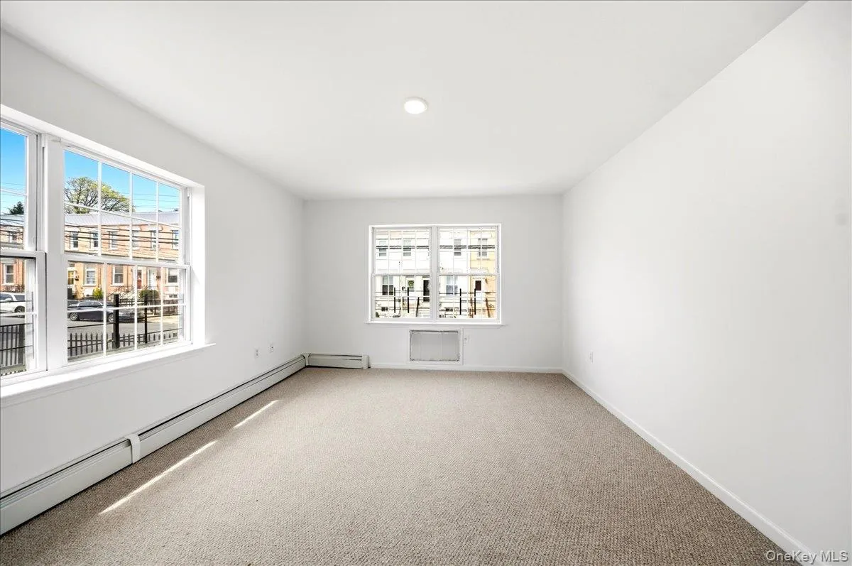 Spare room with baseboard heating, carpet flooring, and plenty of natural light Spare room with baseboard heating, carpet flooring, and plenty of natural light