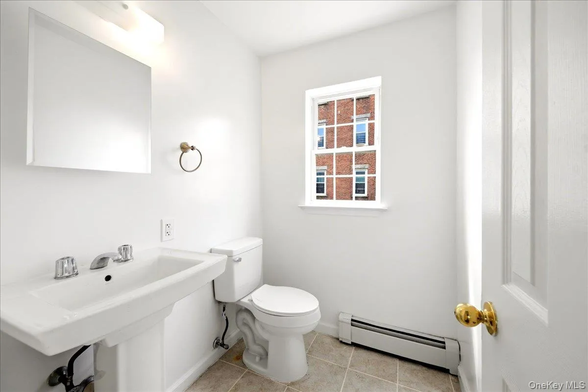 Half bath featuring a baseboard heating unit and light tile patterned floors Half bath featuring a baseboard heating unit and light tile patterned floors