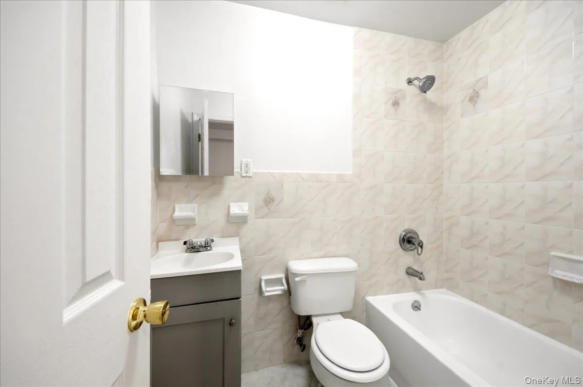 Full bathroom with tile walls, vanity, and shower / tub combination Full bathroom with tile walls, vanity, and shower / tub combination