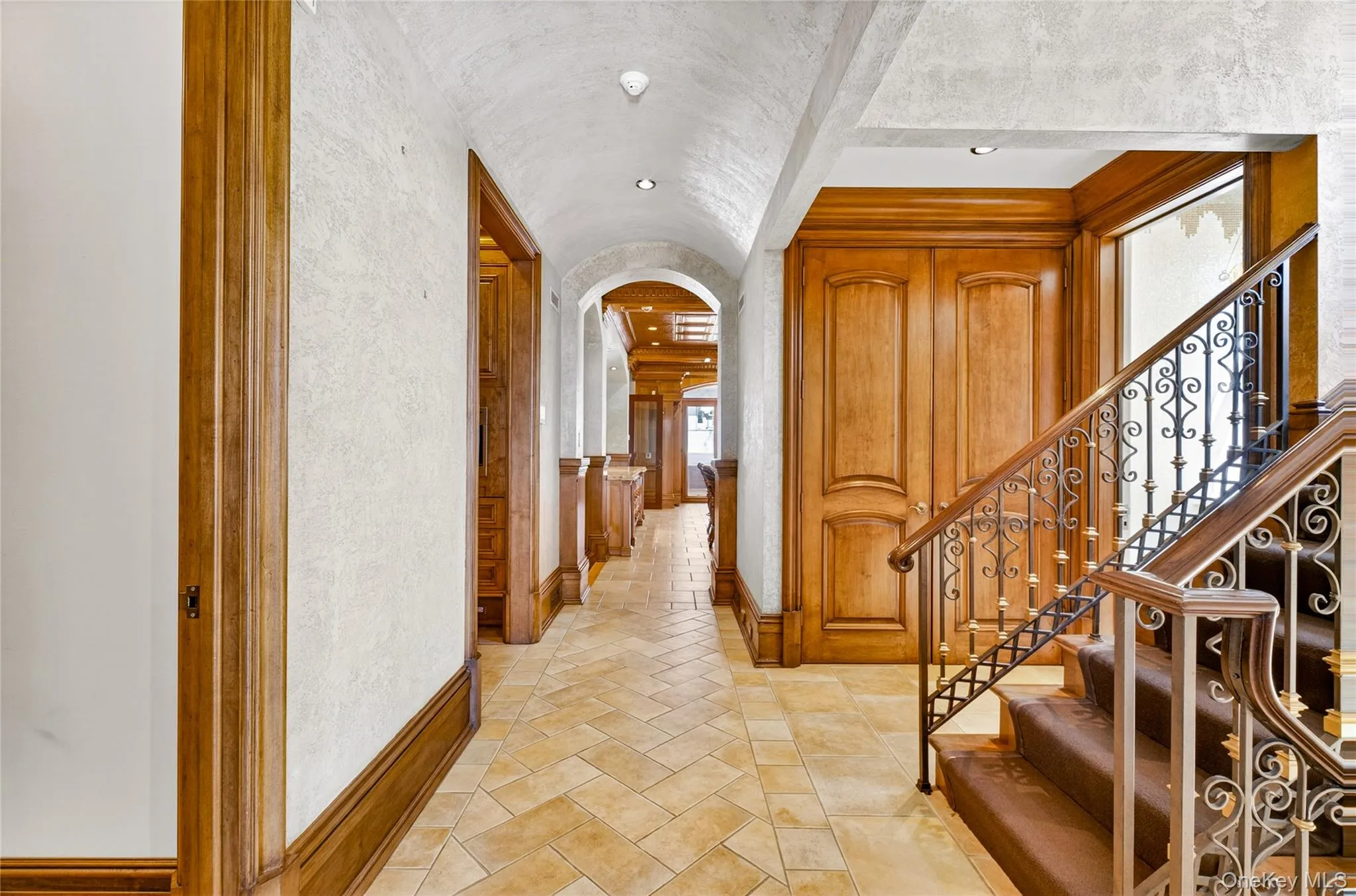 Corridor featuring arched walkways, recessed lighting, and a textured wall Corridor featuring arched walkways, recessed lighting, and a textured wall