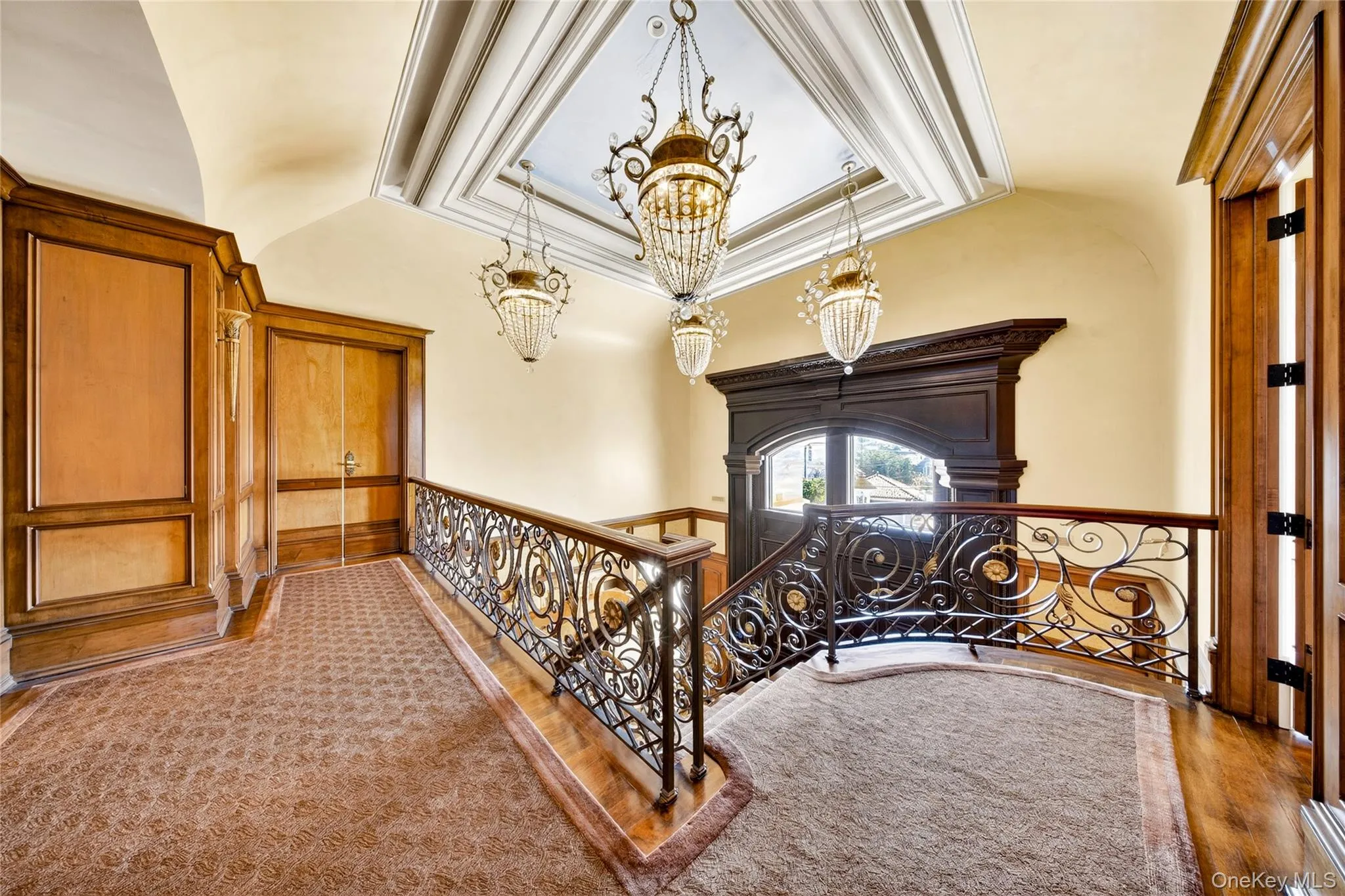 Hallway with hanging lights, a tray ceiling, crown molding, an upstairs landing, and carpet Hallway with hanging lights, a tray ceiling, crown molding, an upstairs landing, and carpet