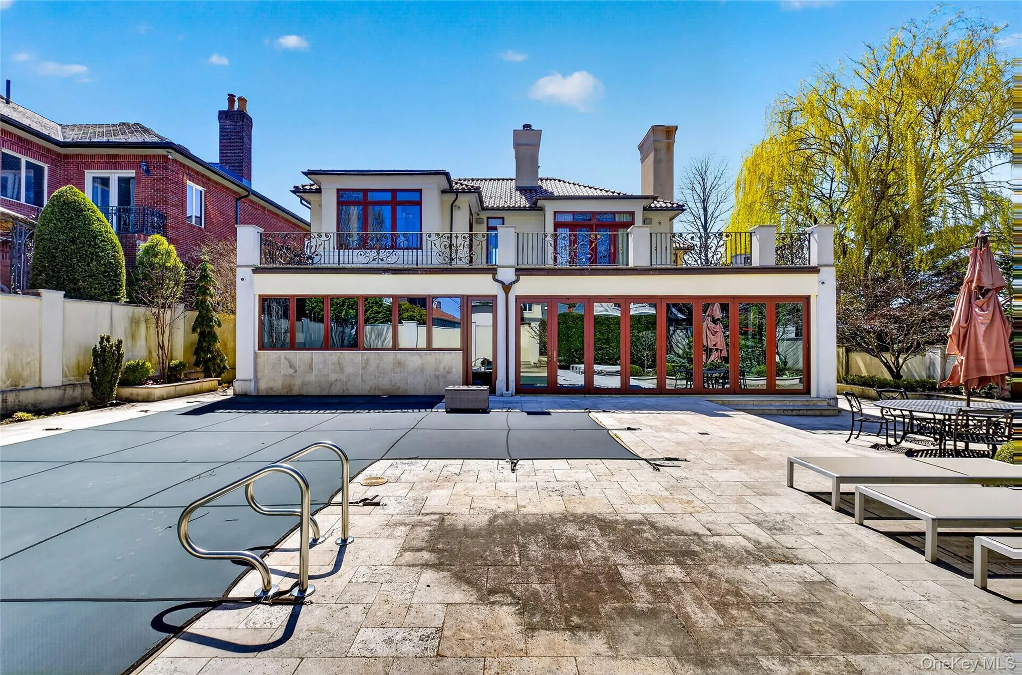 Back of house with a balcony, stucco siding, a patio, and a chimney Back of house with a balcony, stucco siding, a patio, and a chimney