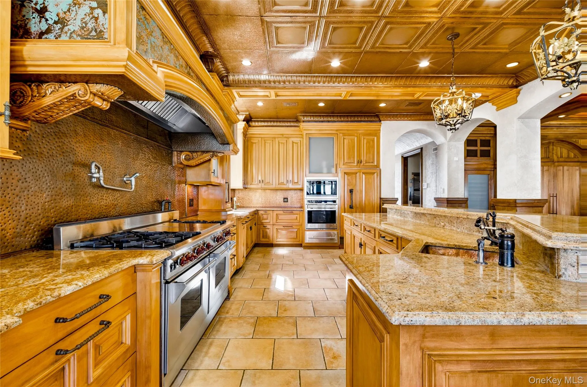 Kitchen featuring an ornate ceiling, stainless steel appliances, light stone counters, decorative backsplash, and arched walkways Kitchen featuring an ornate ceiling, stainless steel appliances, light stone counters, decorative backsplash, and arched walkways