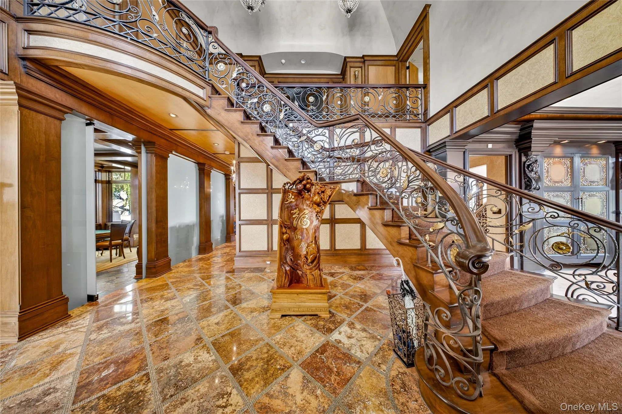 Entryway featuring a grand staircase with ornate wrought iron railings and a carpeted tread Entryway featuring a grand staircase with ornate wrought iron railings and a carpeted tread