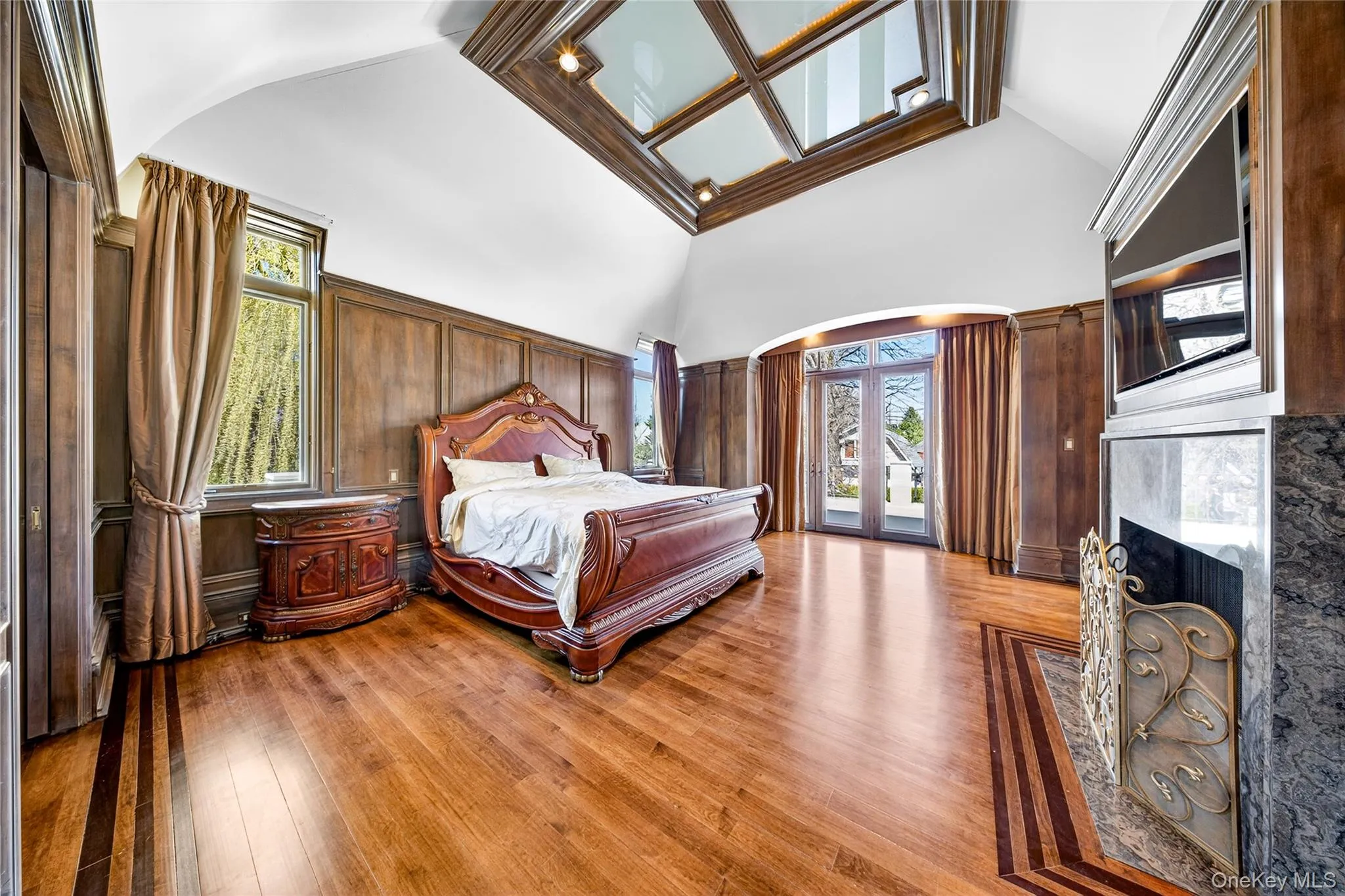 Bedroom with arched walkways, access to exterior, light wood-style flooring, and a fireplace Bedroom with arched walkways, access to exterior, light wood-style flooring, and a fireplace