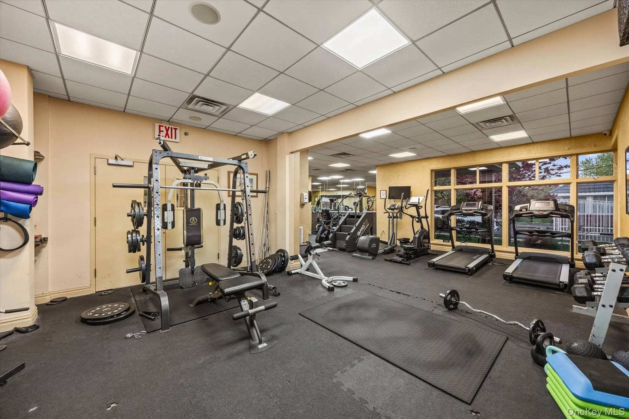Dedicated fitness room featuring recessed lighting, a drop ceiling, and large windows Dedicated fitness room featuring recessed lighting, a drop ceiling, and large windows