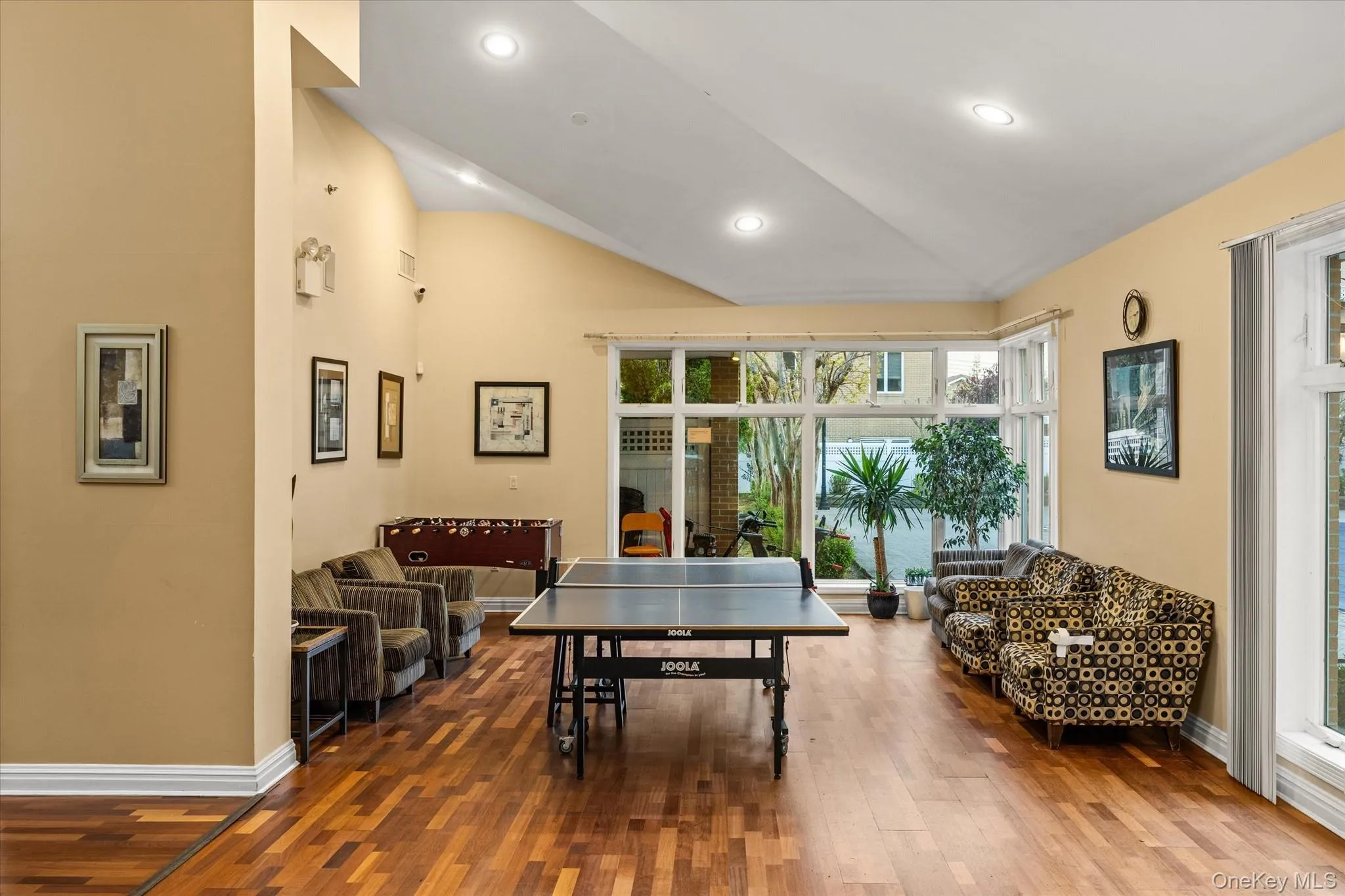 Spacious entertainment room featuring wood-finish flooring and a high vaulted ceiling Spacious entertainment room featuring wood-finish flooring and a high vaulted ceiling