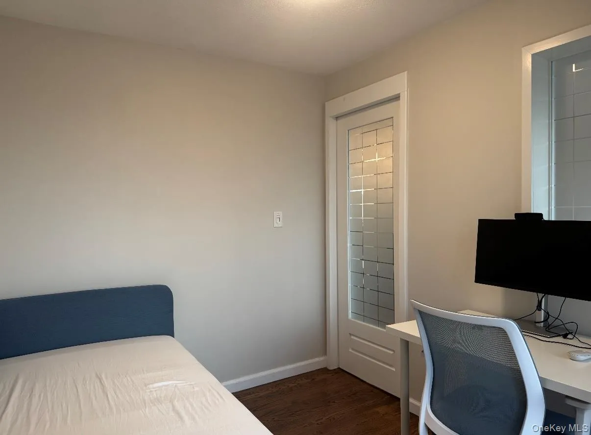 Bedroom featuring an office area and dark wood-style flooring Bedroom featuring an office area and dark wood-style flooring