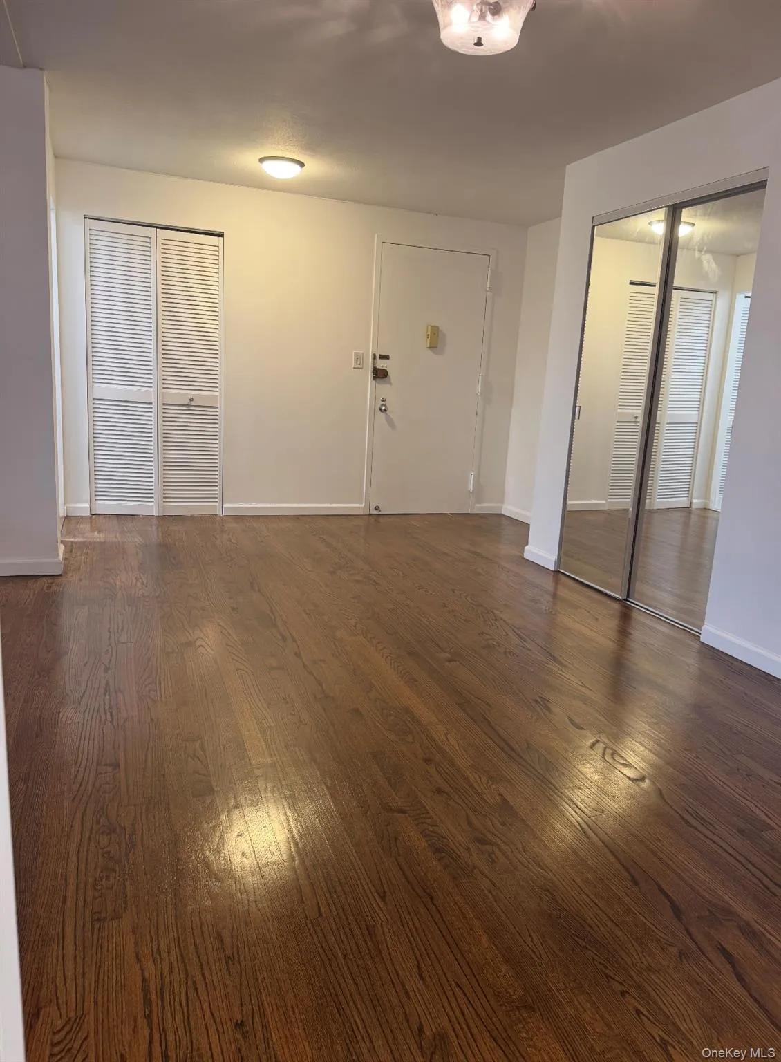 Unfurnished living room with dark wood-style floors and baseboards Unfurnished living room with dark wood-style floors and baseboards