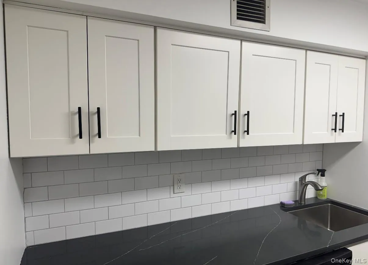 Kitchen view of white cabinets and dark stone countertops Kitchen view of white cabinets and dark stone countertops