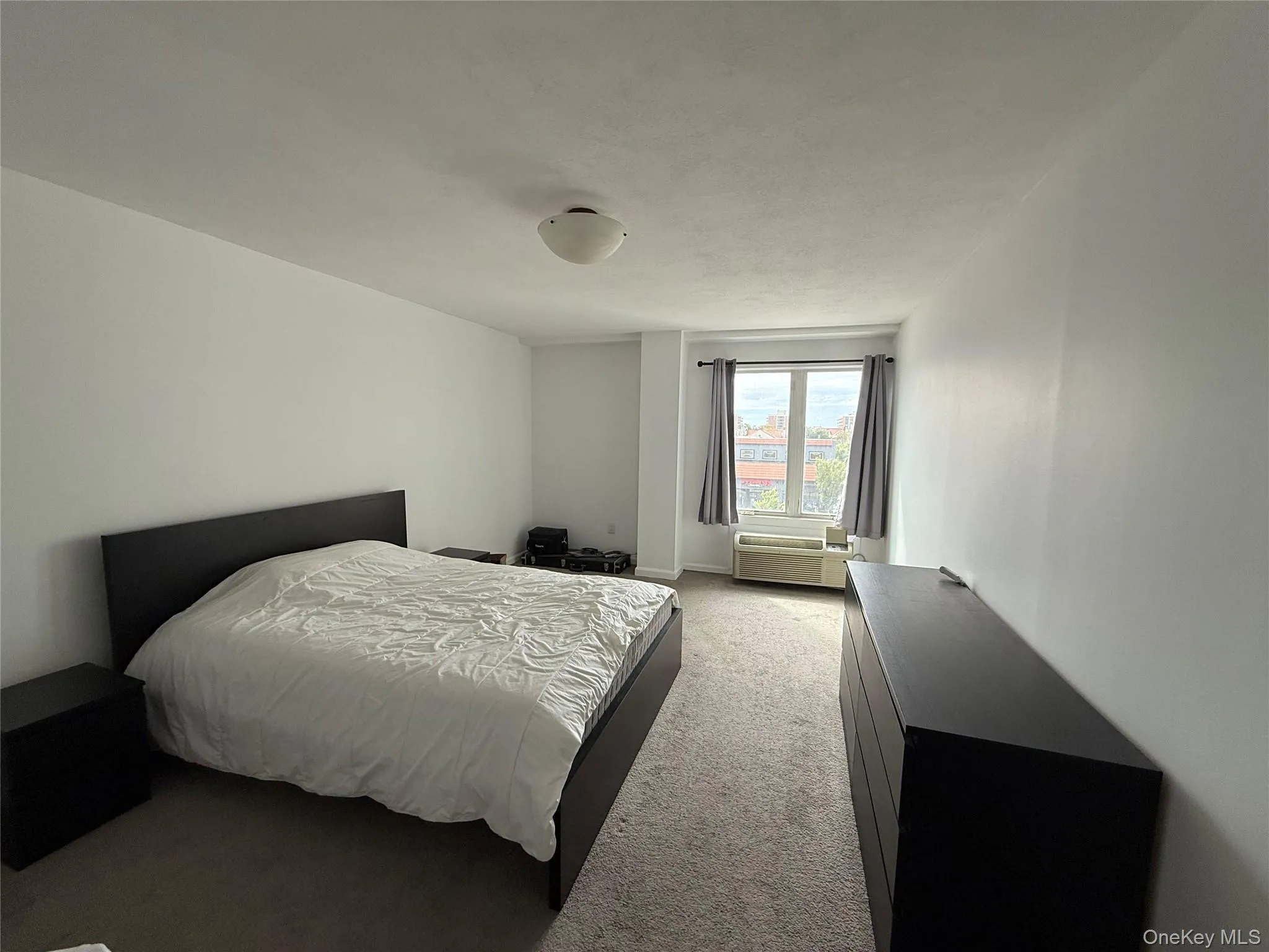 Bedroom featuring light carpet and a wall mounted air conditioner Bedroom featuring light carpet and a wall mounted air conditioner