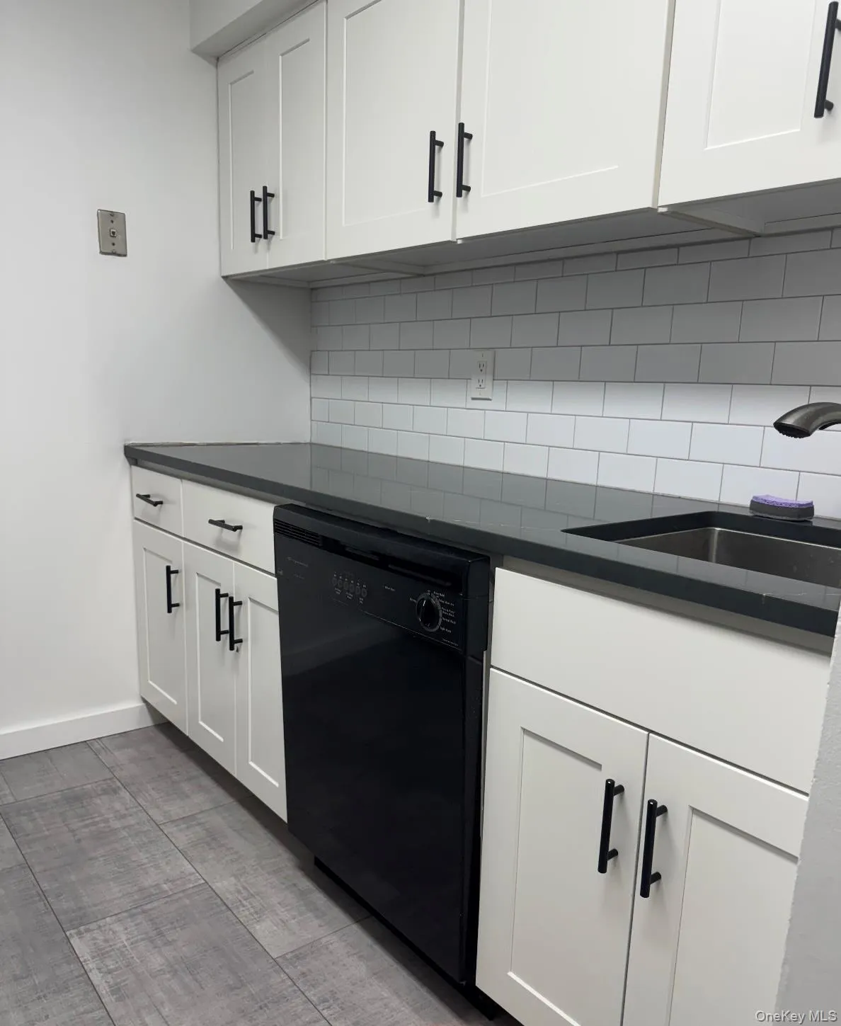 Kitchen featuring black dishwasher, white cabinets, and decorative backsplash Kitchen featuring black dishwasher, white cabinets, and decorative backsplash