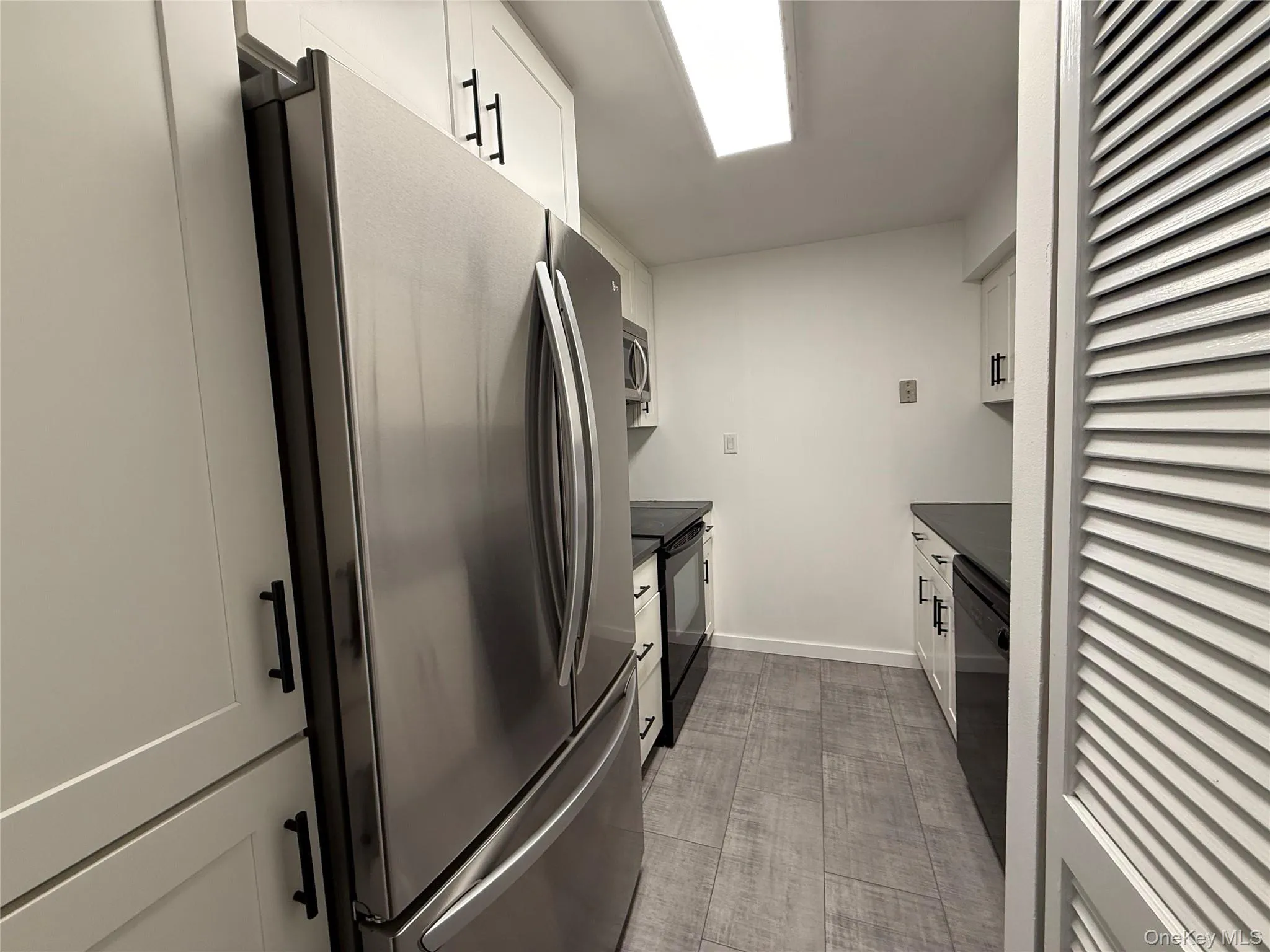Kitchen featuring black appliances, white cabinetry, and dark countertops Kitchen featuring black appliances, white cabinetry, and dark countertops