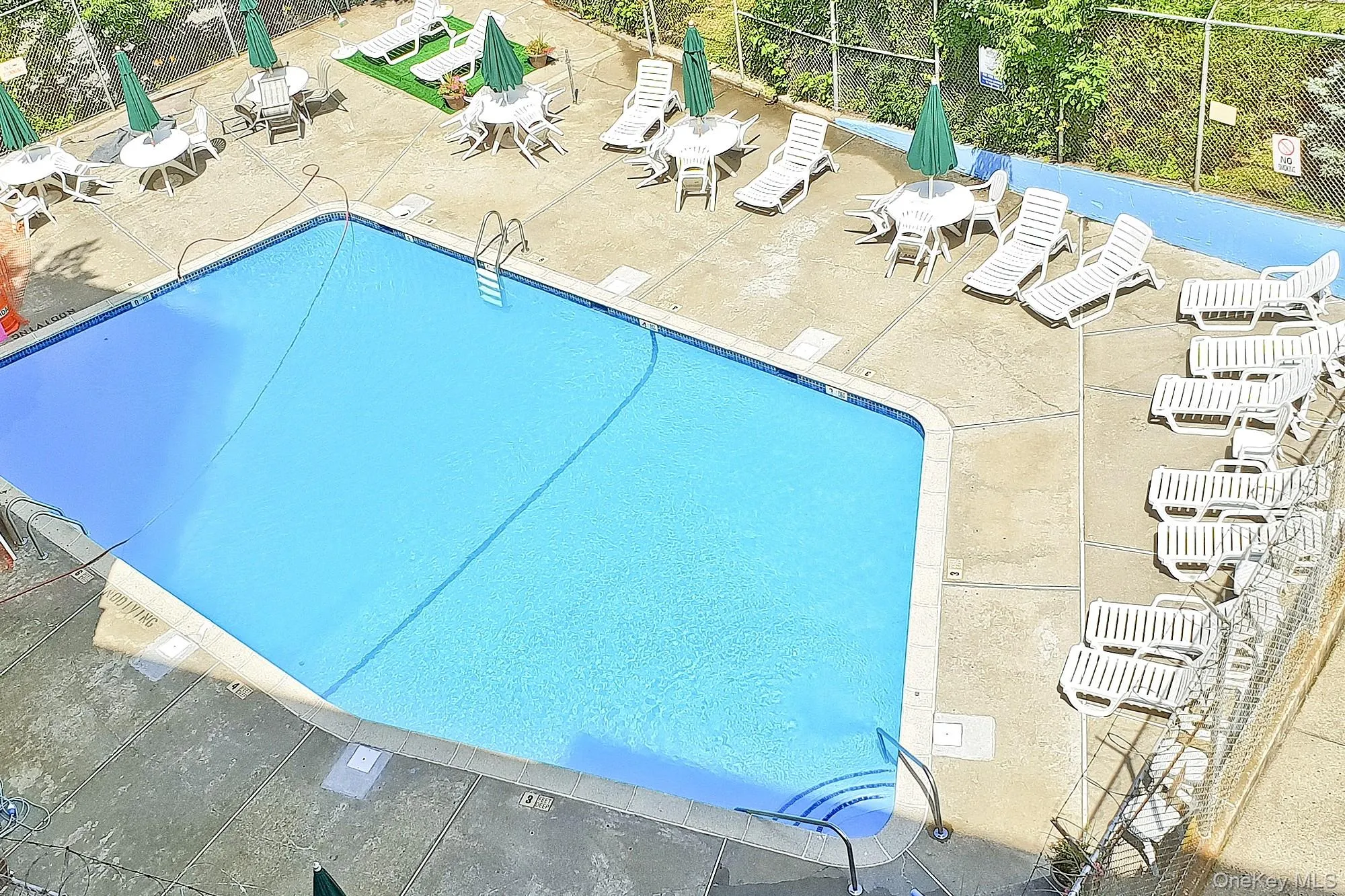 Large outdoor pool with a pool deck that features lounge chairs Large outdoor pool with a pool deck that features lounge chairs