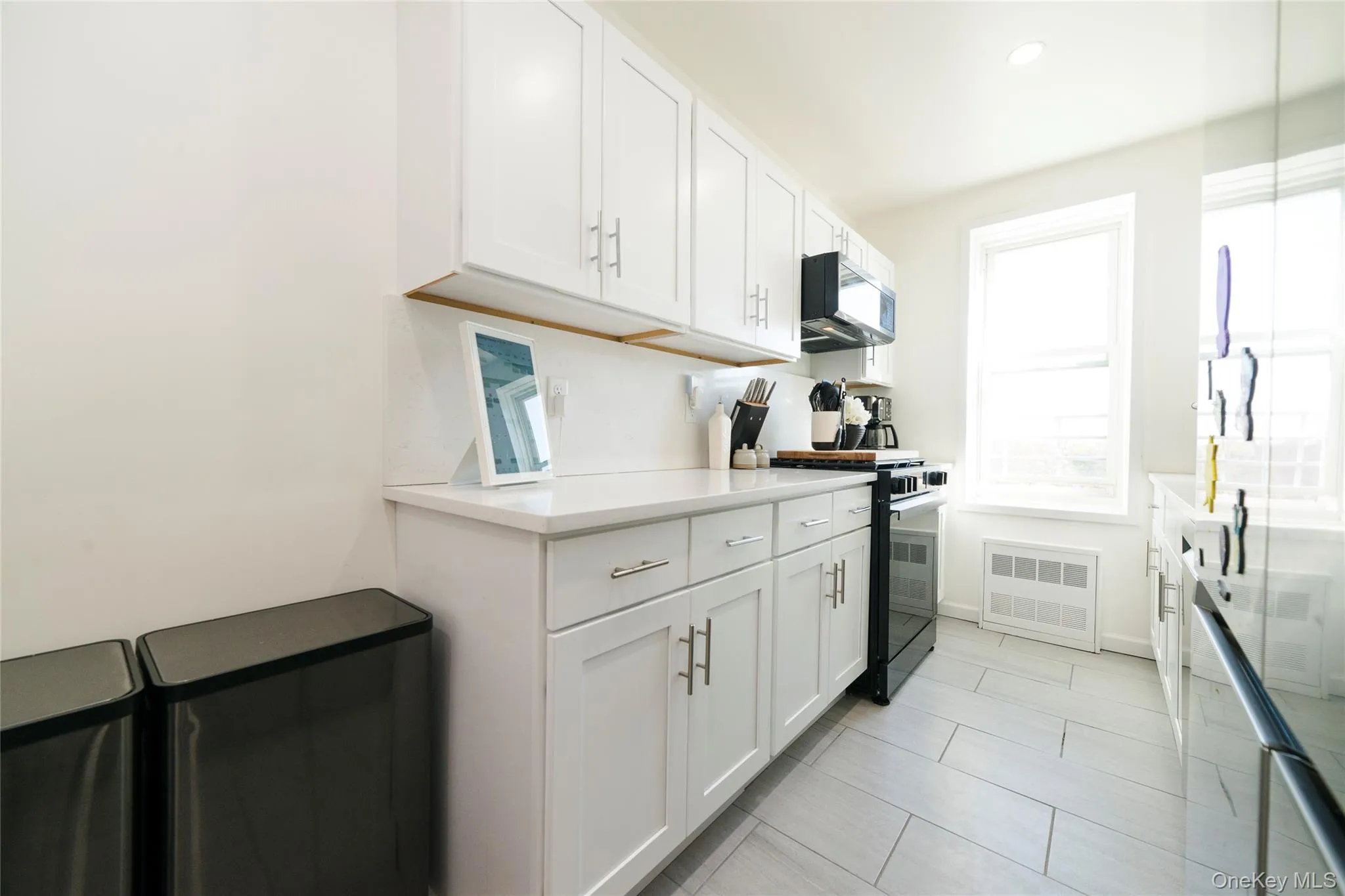 The eat-in kitchen is appointed with white cabinetry, quartz countertops, a stainless steel refrigerator featuring a wine cooler and icemaker, a microwave over a full gas range, and a window with Sound views that fills the space with natural light—an ideal spot to enjoy your morning coffee. The eat-in kitchen is appointed with white cabinetry, quartz countertops, a stainless steel refrigerator featuring a wine cooler and icemaker, a microwave over a full gas range, and a window with Sound views that fills the space with natural light—an ideal spot to enjoy your morning coffee.
