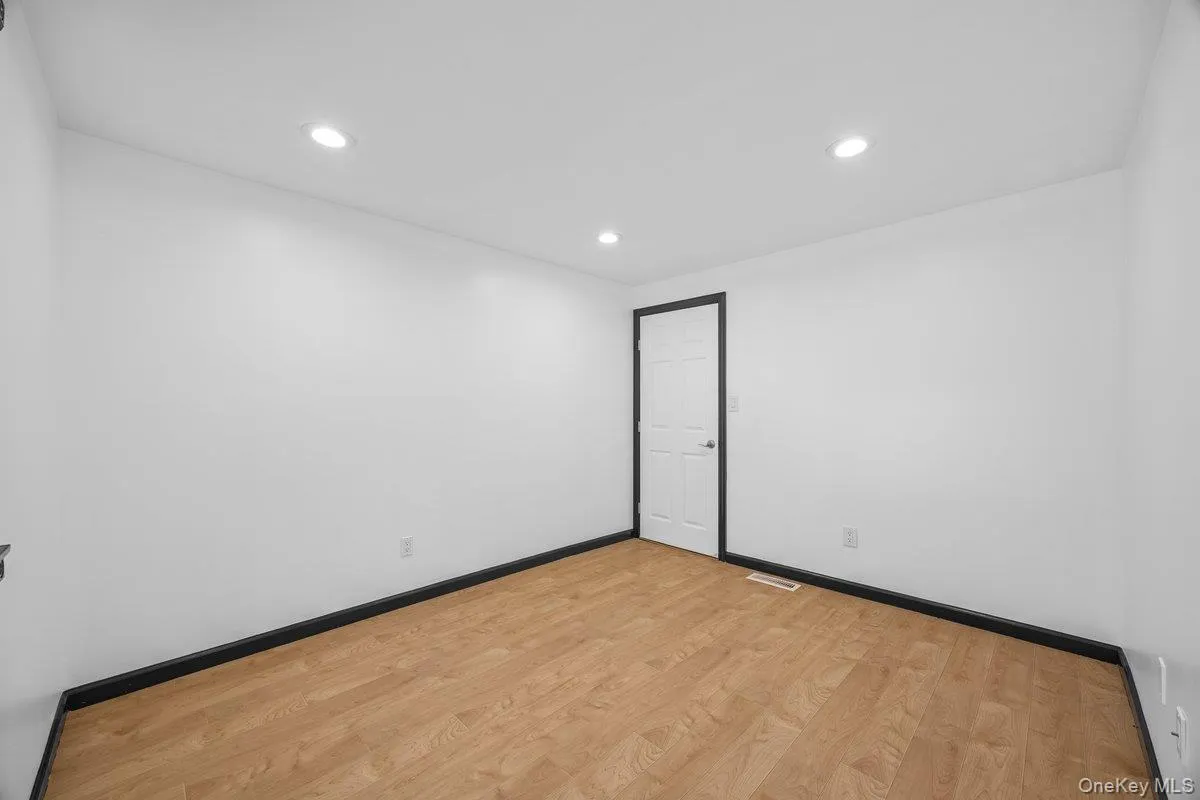 This room features light wood flooring, white walls, and recessed lighting This room features light wood flooring, white walls, and recessed lighting