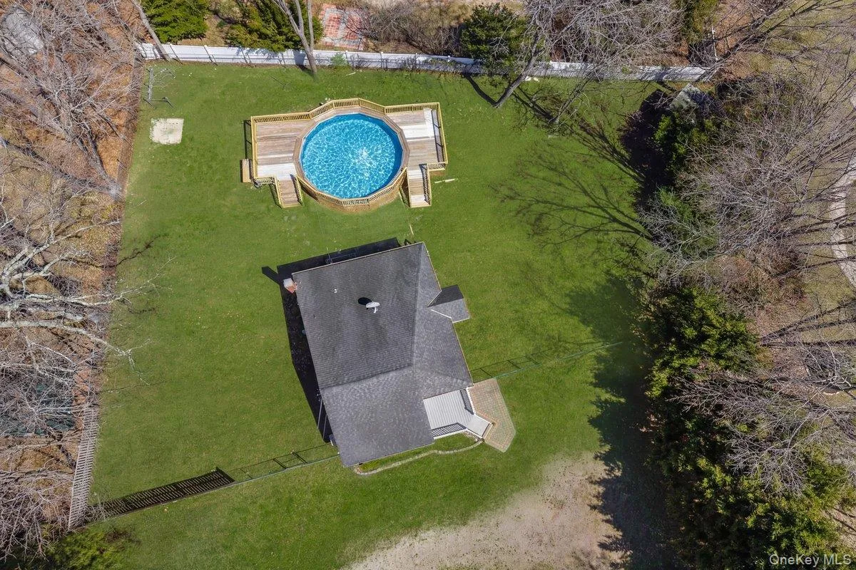An aerial view of the property showcasing a private pool with a surrounding deck, a well-maintained lawn, and a fenced area An aerial view of the property showcasing a private pool with a surrounding deck, a well-maintained lawn, and a fenced area
