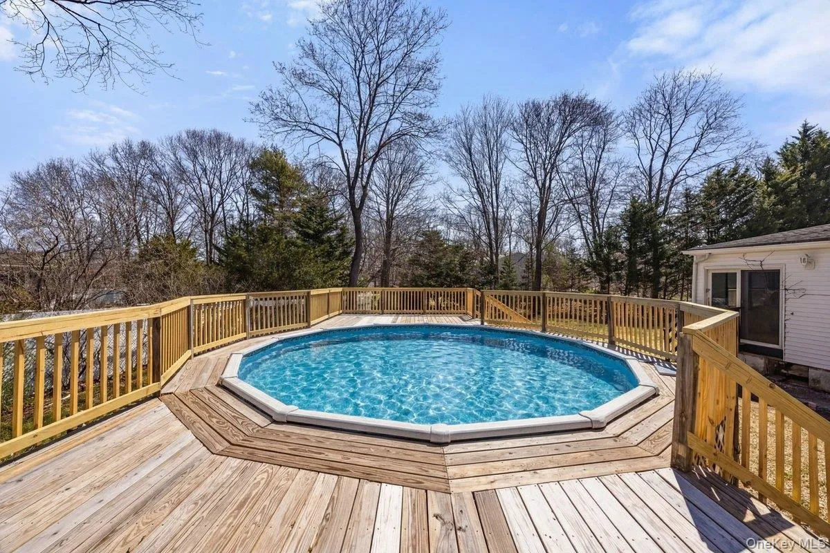 The property features an outdoor swimming pool surrounded by a wooden deck with railing The property features an outdoor swimming pool surrounded by a wooden deck with railing