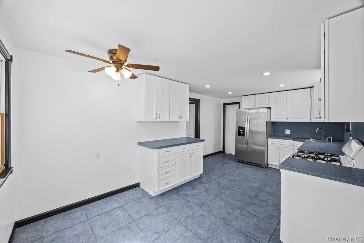 Kitchen featuring white cabinetry, blue countertops, blue tile flooring, and a stainless steel refrigerator Kitchen featuring white cabinetry, blue countertops, blue tile flooring, and a stainless steel refrigerator