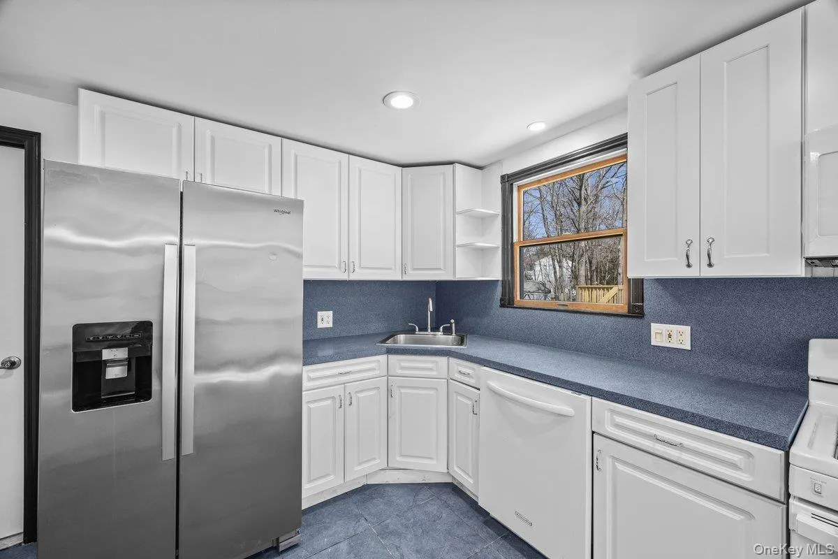 The kitchen features white cabinetry, blue countertops, and a stainless steel side-by-side refrigerator The kitchen features white cabinetry, blue countertops, and a stainless steel side-by-side refrigerator