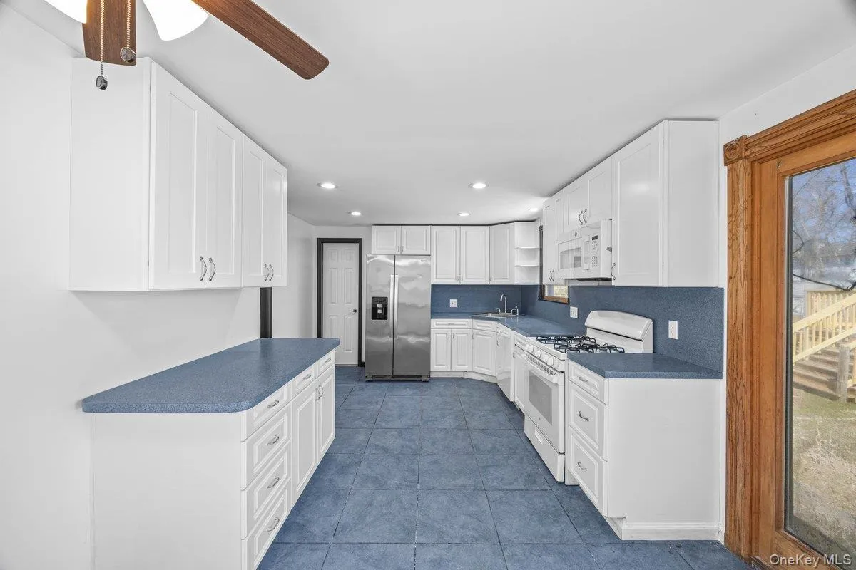The kitchen features white cabinetry, blue countertops, and a white oven with a range The kitchen features white cabinetry, blue countertops, and a white oven with a range