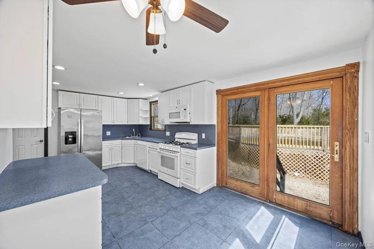 The kitchen features white cabinetry, stainless steel appliances, blue countertops, and tiled flooring The kitchen features white cabinetry, stainless steel appliances, blue countertops, and tiled flooring