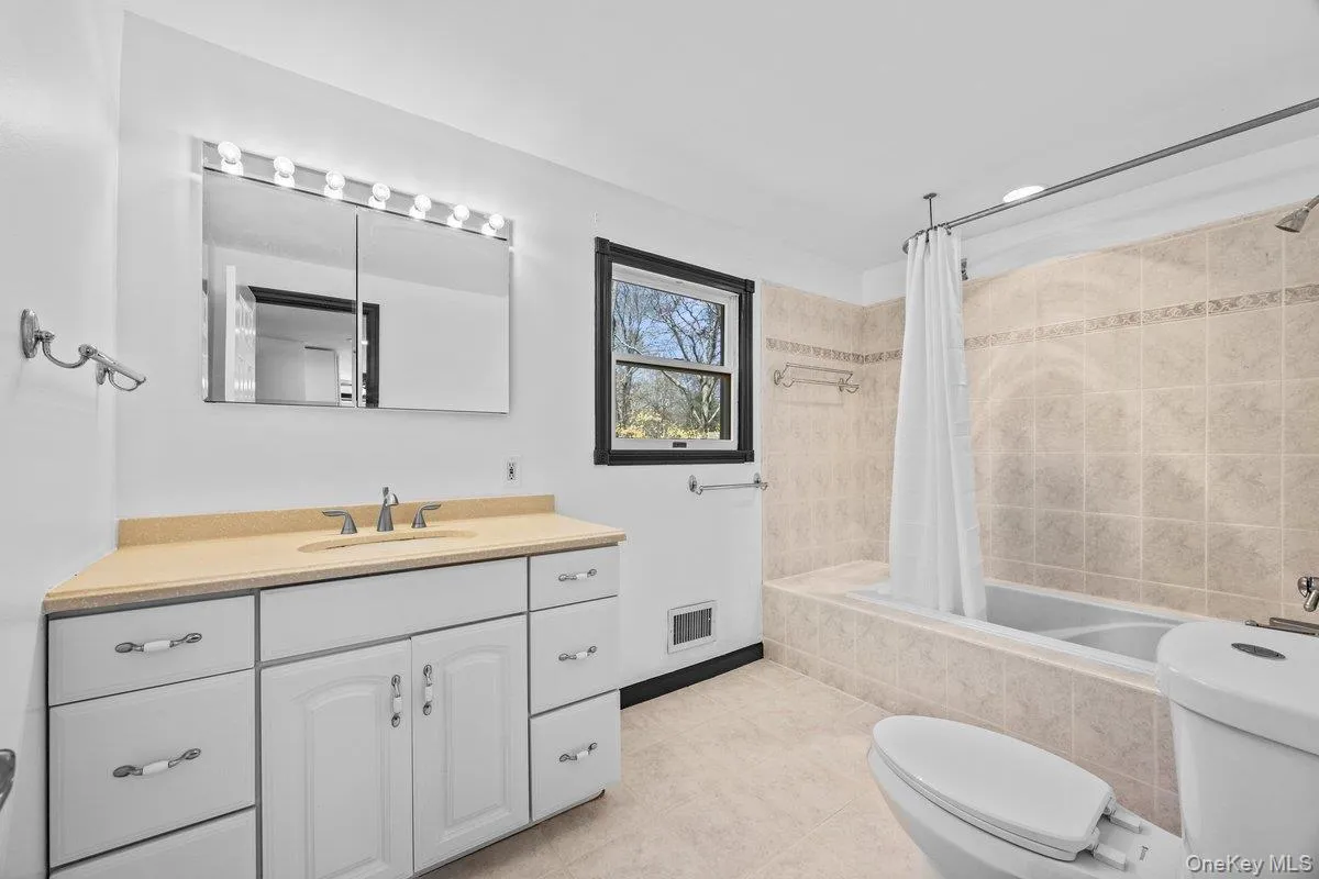 The bathroom features a vanity with a light-colored countertop and a mirror with integrated lighting The bathroom features a vanity with a light-colored countertop and a mirror with integrated lighting