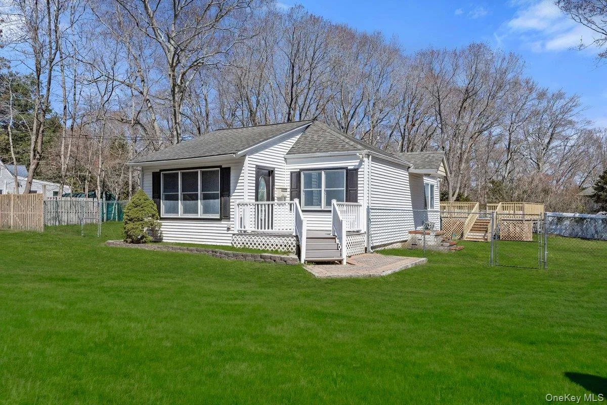 The property features a well-maintained lawn and a front porch with white railings and steps The property features a well-maintained lawn and a front porch with white railings and steps