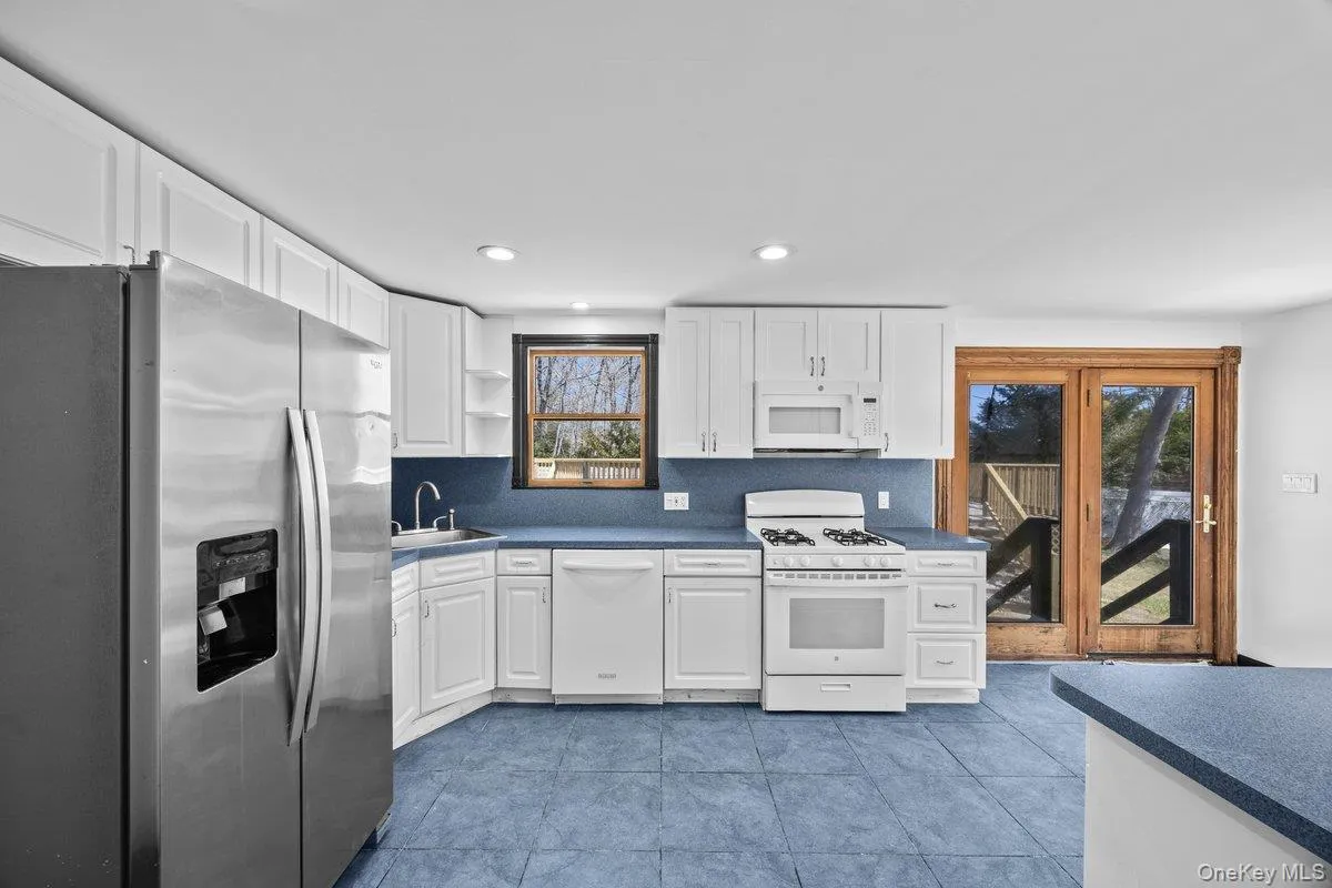 The kitchen features white cabinetry, stainless steel appliances, and blue countertops The kitchen features white cabinetry, stainless steel appliances, and blue countertops