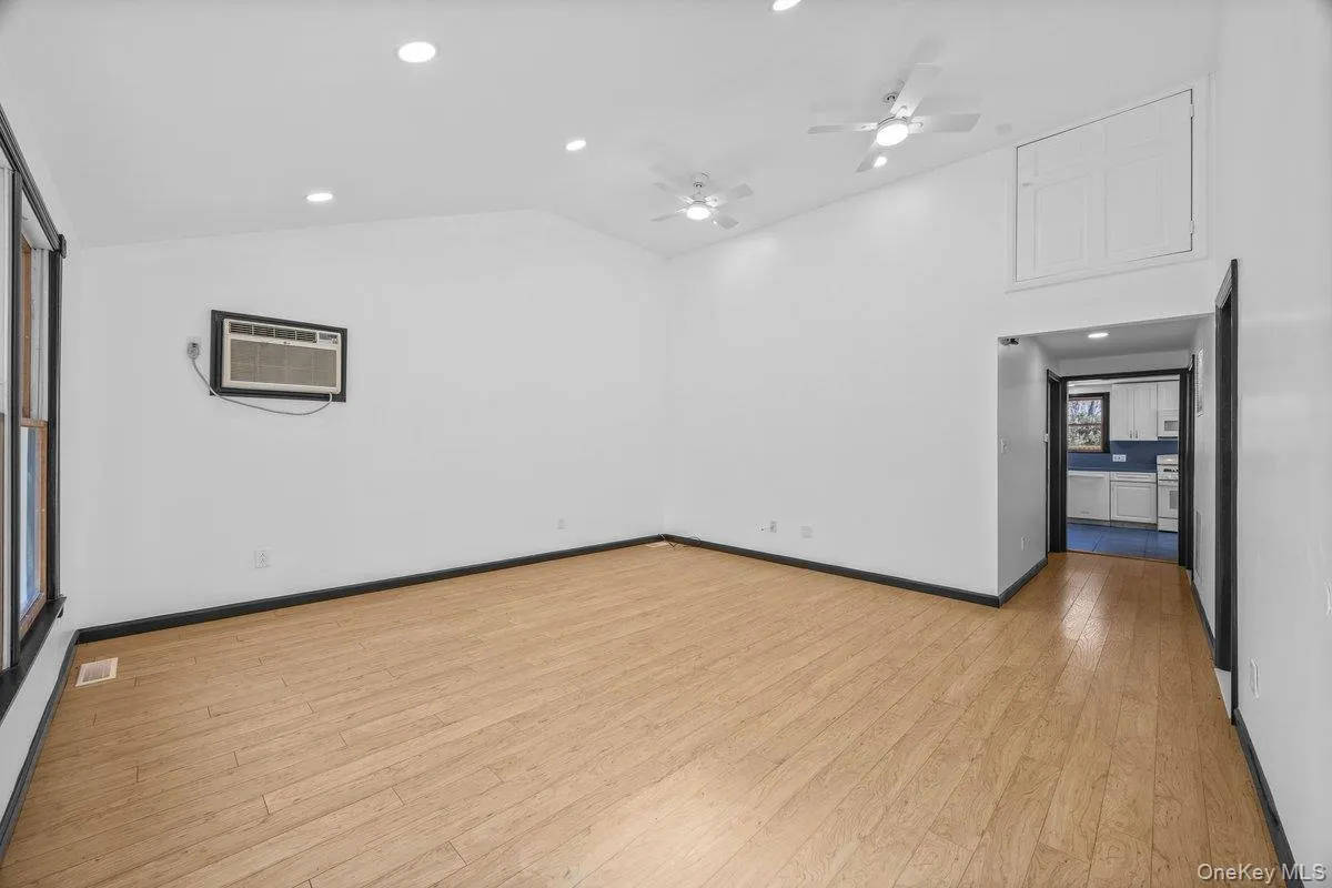 Spacious living area featuring light-toned wood flooring, recessed lighting, and a vaulted ceiling Spacious living area featuring light-toned wood flooring, recessed lighting, and a vaulted ceiling