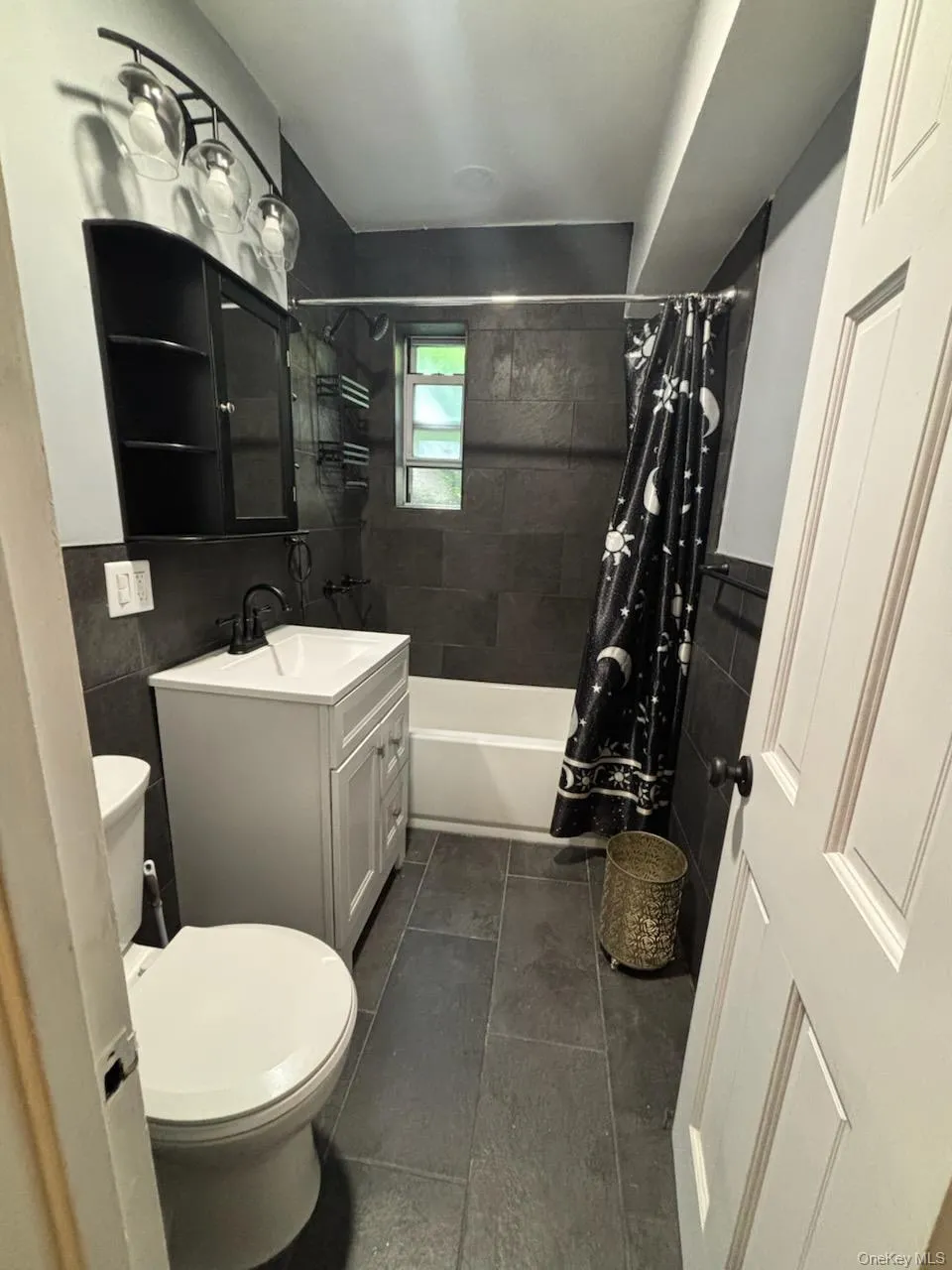 Bathroom featuring dark tile flooring, a white bathtub, and dark subway tile Bathroom featuring dark tile flooring, a white bathtub, and dark subway tile