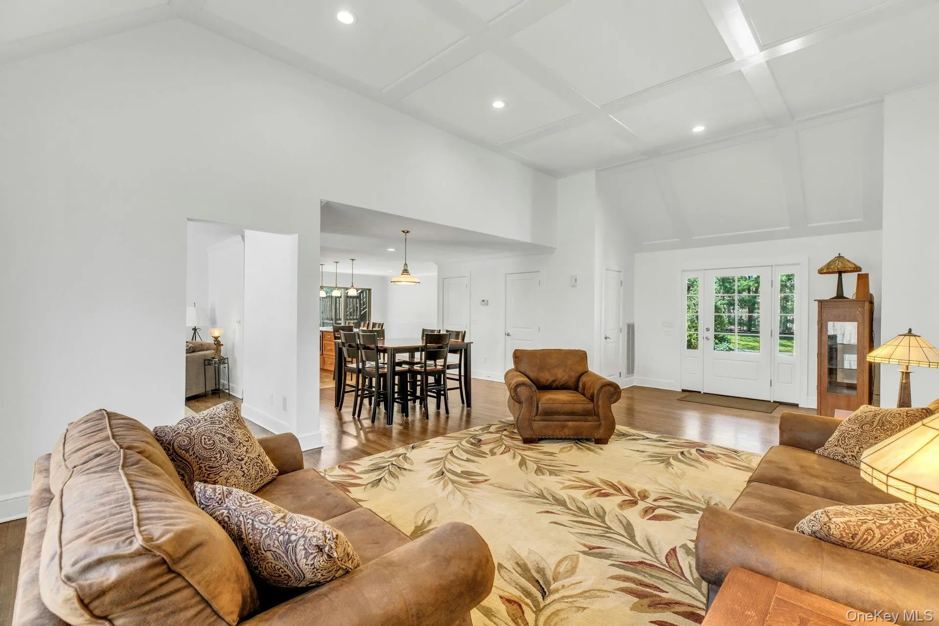 Spacious living area featuring wood-finish flooring, a coffered ceiling, recessed lighting, and a vaulted ceiling Spacious living area featuring wood-finish flooring, a coffered ceiling, recessed lighting, and a vaulted ceiling