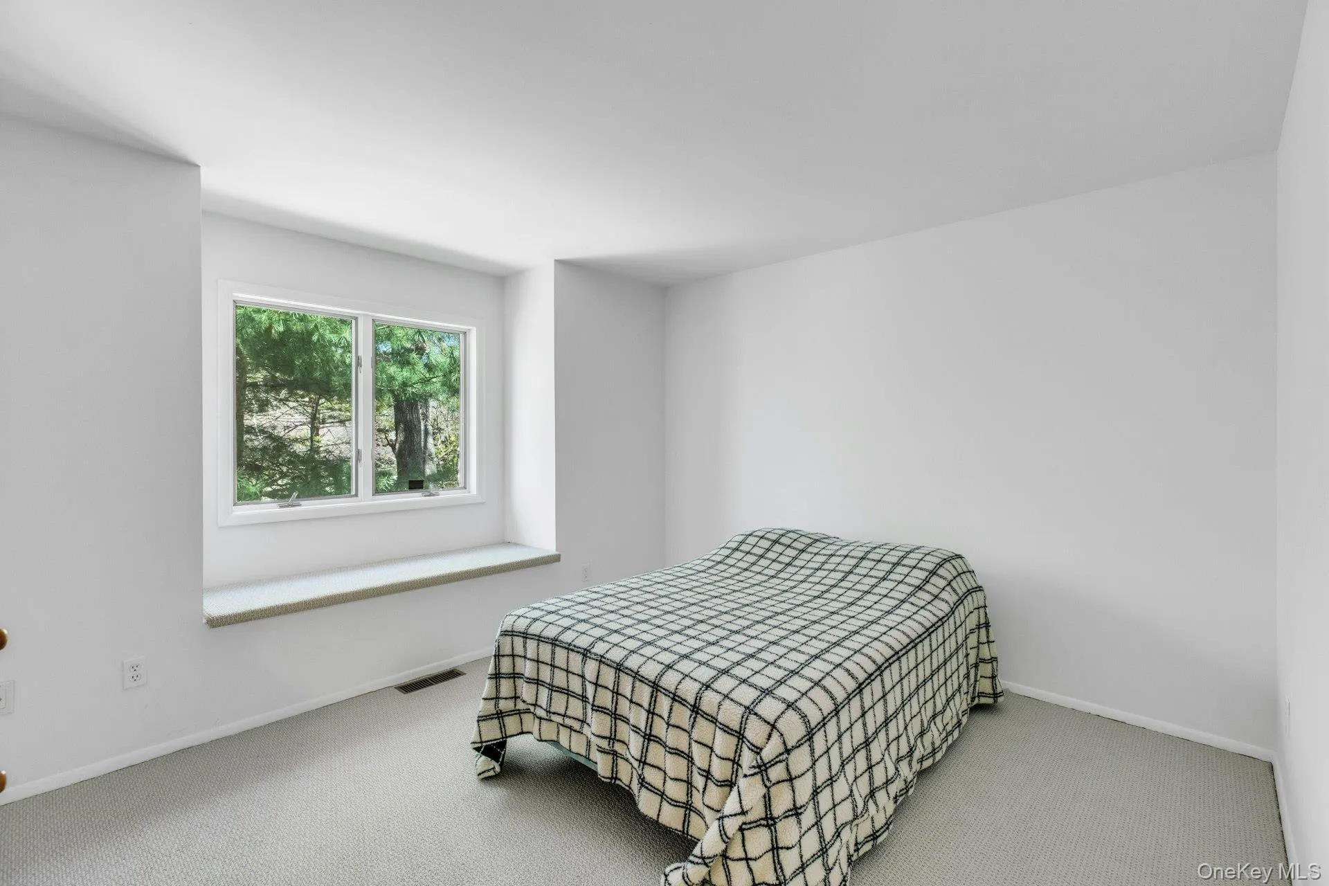 Bright room featuring a large window with a built-in sill and light-colored carpeting Bright room featuring a large window with a built-in sill and light-colored carpeting