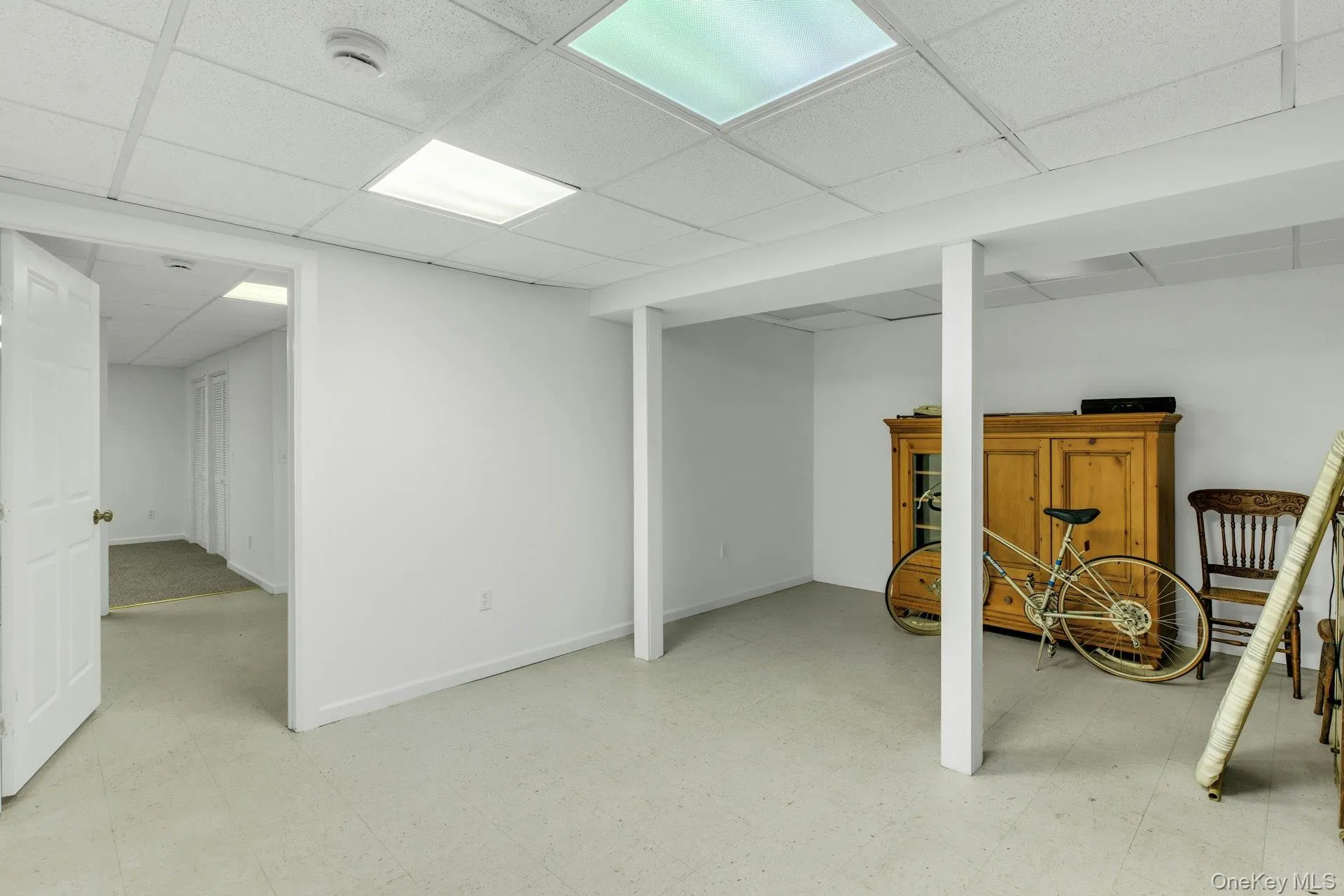 Spacious finished basement offering an open layout, drop ceiling with integrated lighting, white painted walls, and durable light-colored flooring Spacious finished basement offering an open layout, drop ceiling with integrated lighting, white painted walls, and durable light-colored flooring