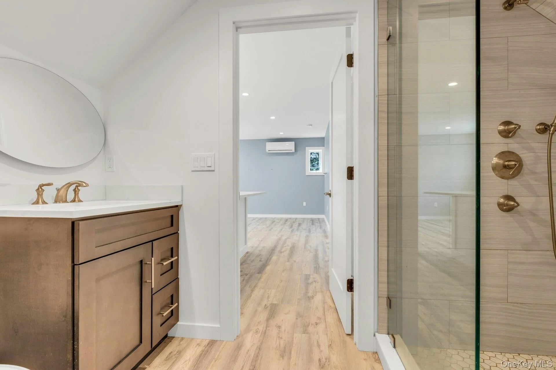 Bathroom featuring a wood-finish vanity with a white countertop and brass-toned fixtures Bathroom featuring a wood-finish vanity with a white countertop and brass-toned fixtures
