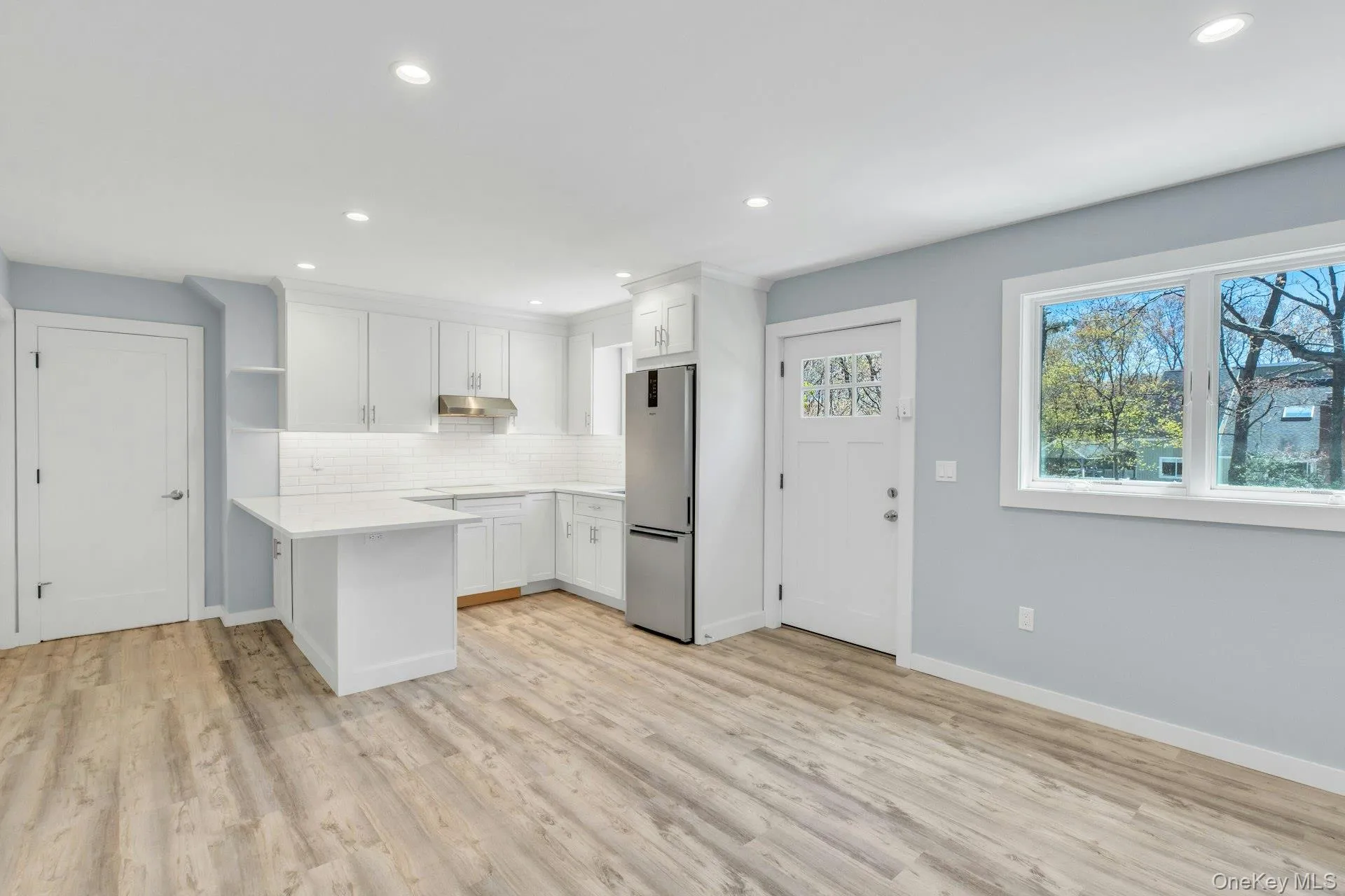 Apartment with Open-concept kitchen and living area featuring wood-finish flooring, recessed lighting, and a kitchen with white cabinetry Apartment with Open-concept kitchen and living area featuring wood-finish flooring, recessed lighting, and a kitchen with white cabinetry